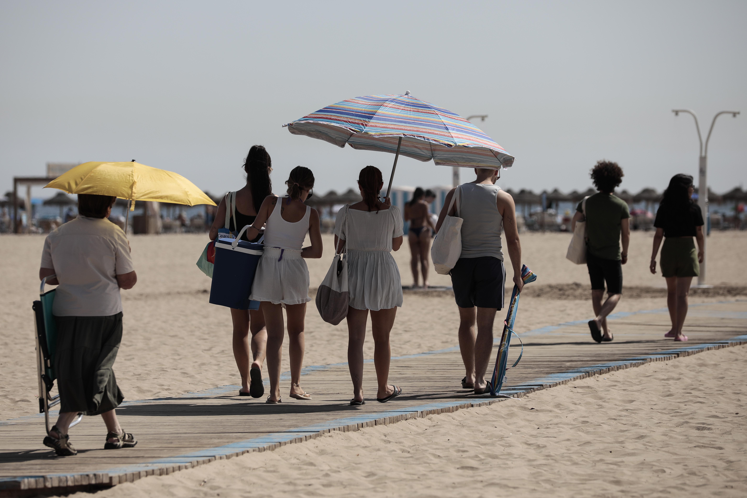 Los baistas se protegen del sol camino de la playa de las Arenas, en Valencia.