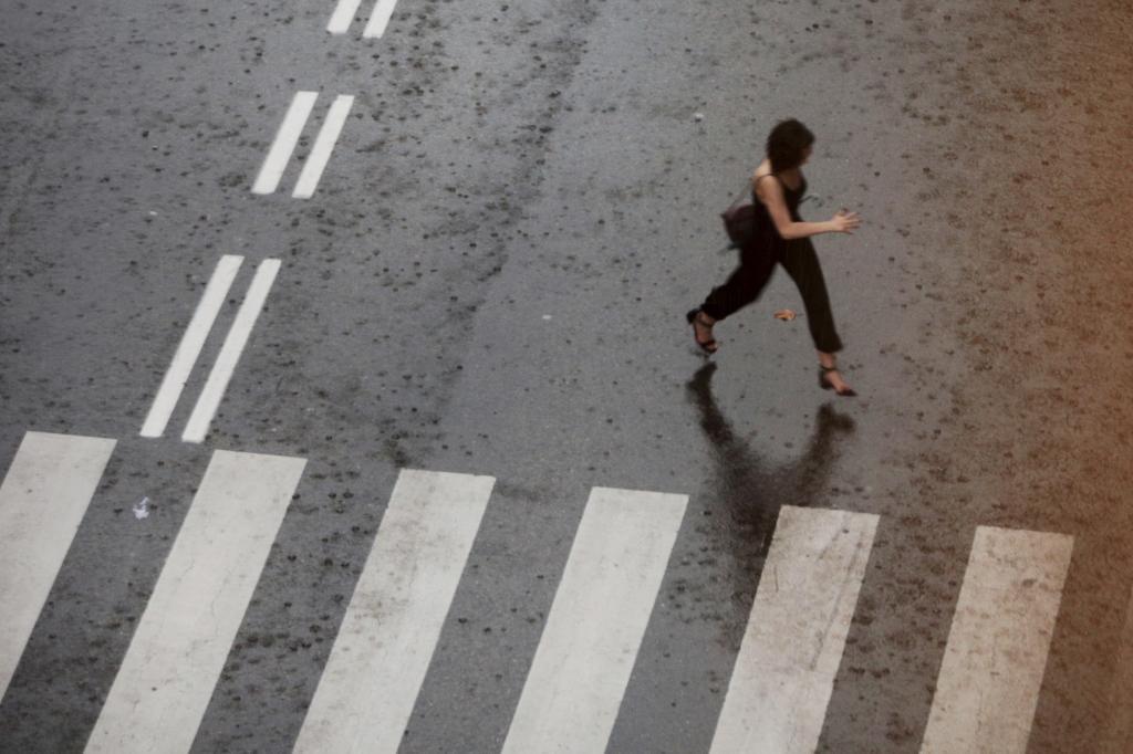 Una madrilea cruza una calle con lluvia.