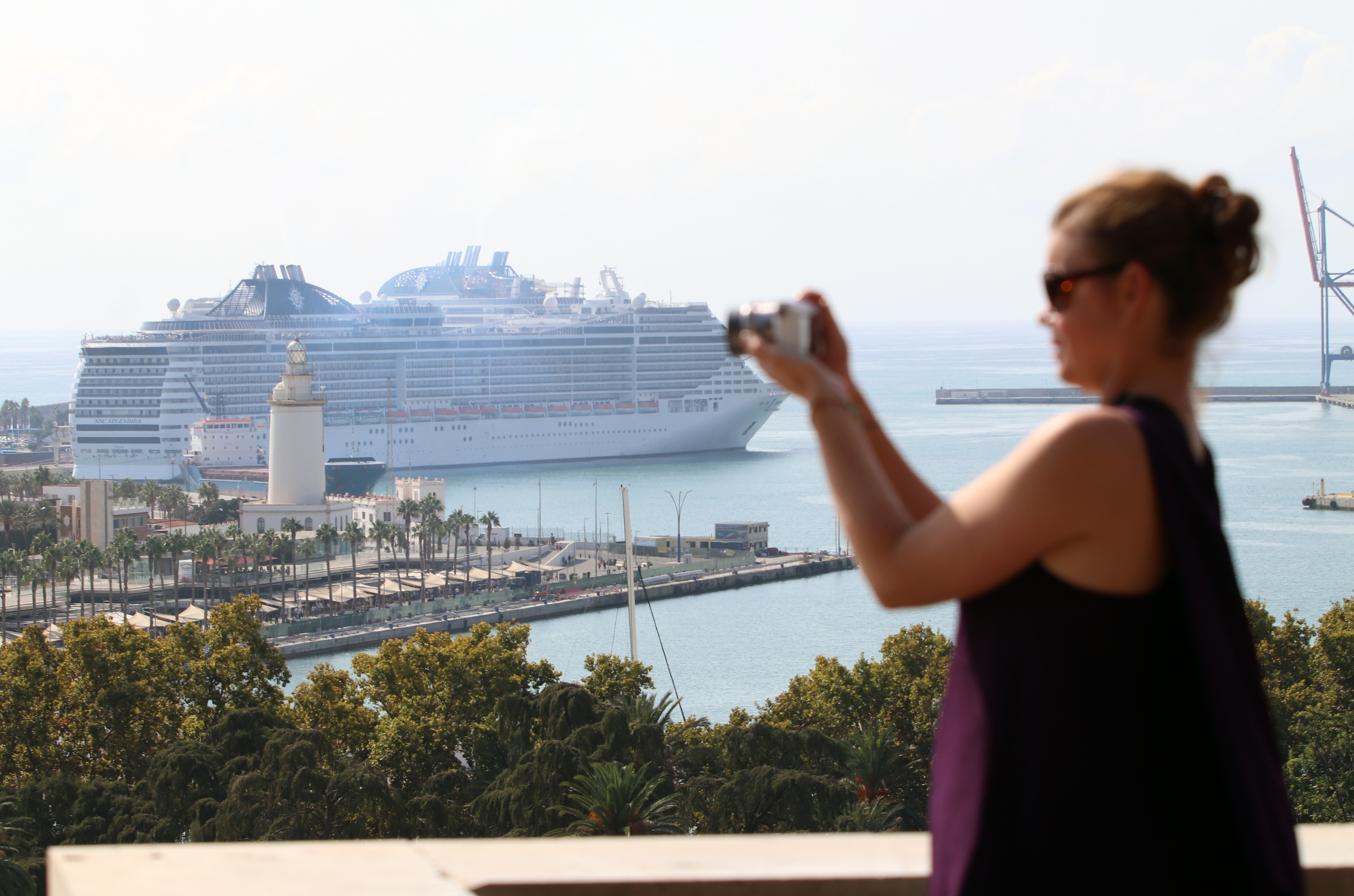 Un mujer toma una foto delante de un crucero atracado en el Puerto de Mlaga.