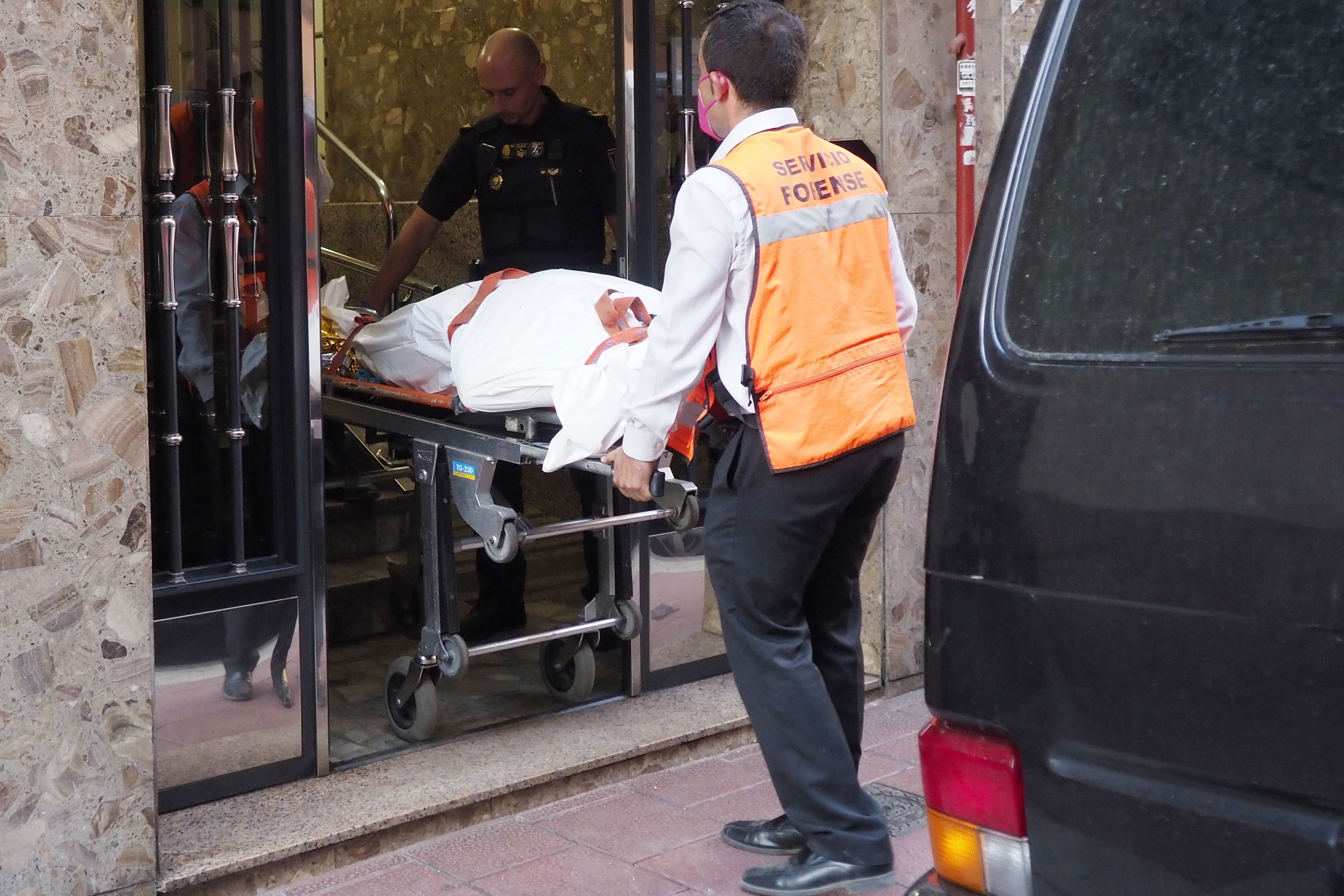 Empleados de los servicios funerarios sacan un cadáver de una de las viviendas de Valladolid donde se produjeron los asesinatos.