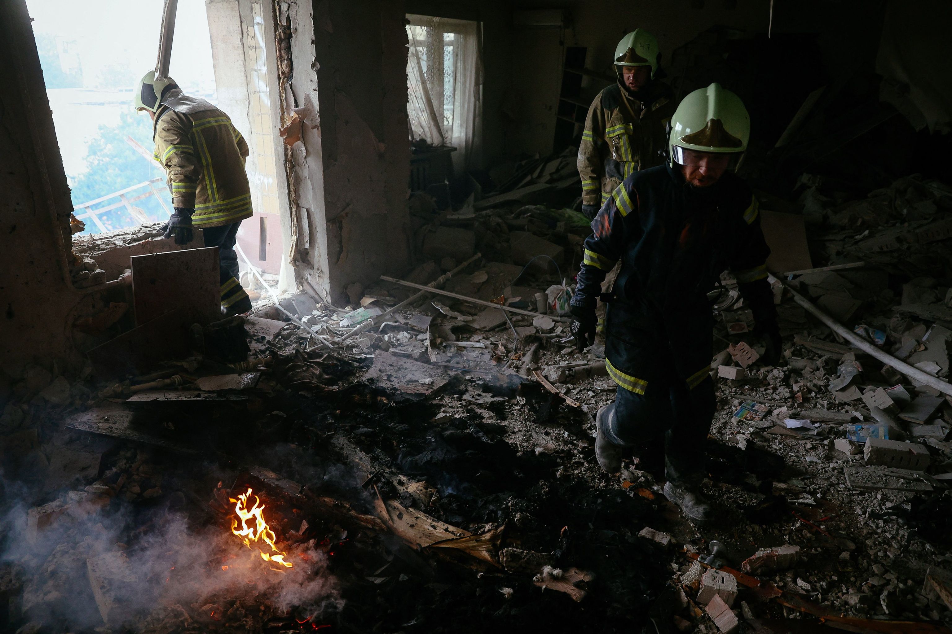 Los bomberos tratan de apagar el fuego en un edificio alcanzado por un bombardeo