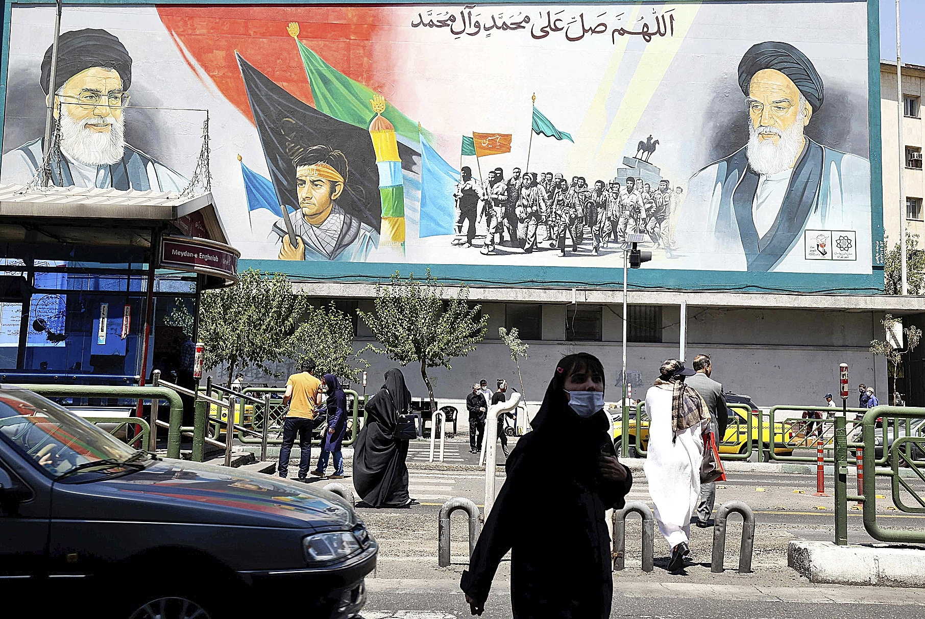 Iraníes caminan frente a una valla con retratos del ayatolá Jamenei.