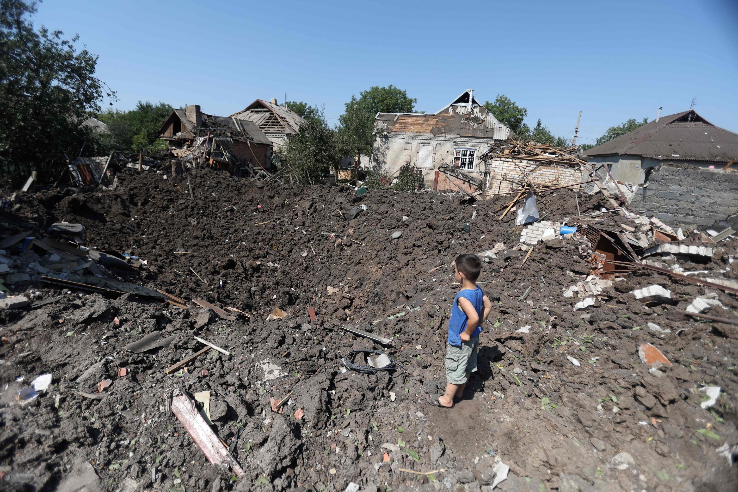Un niño mira un cráter tras un ataque en el  en el pueblo de Druzhkivka, en la región de Donetsk.