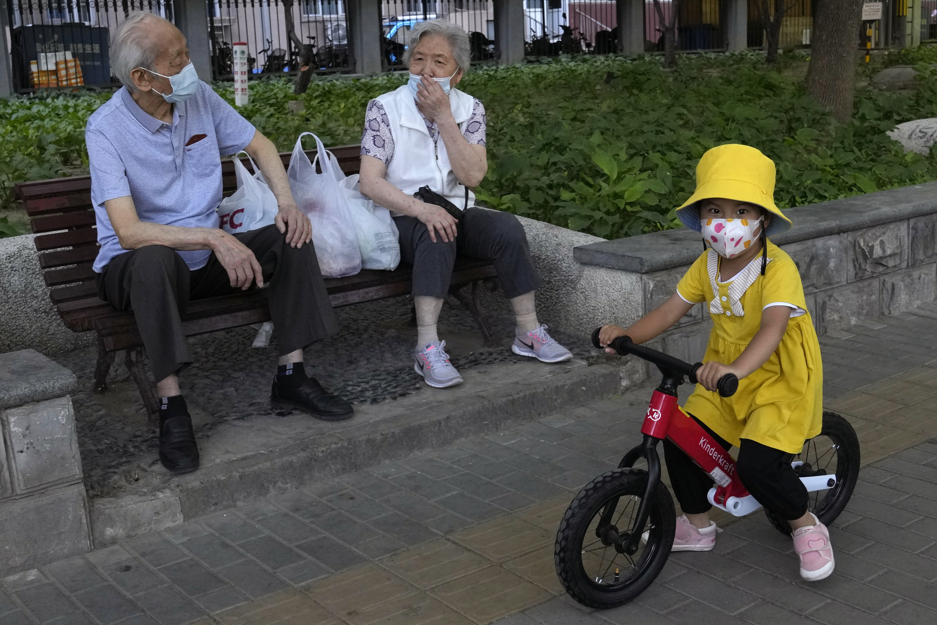 Una niña camina delante de una pareja de ancianos en Pekín.