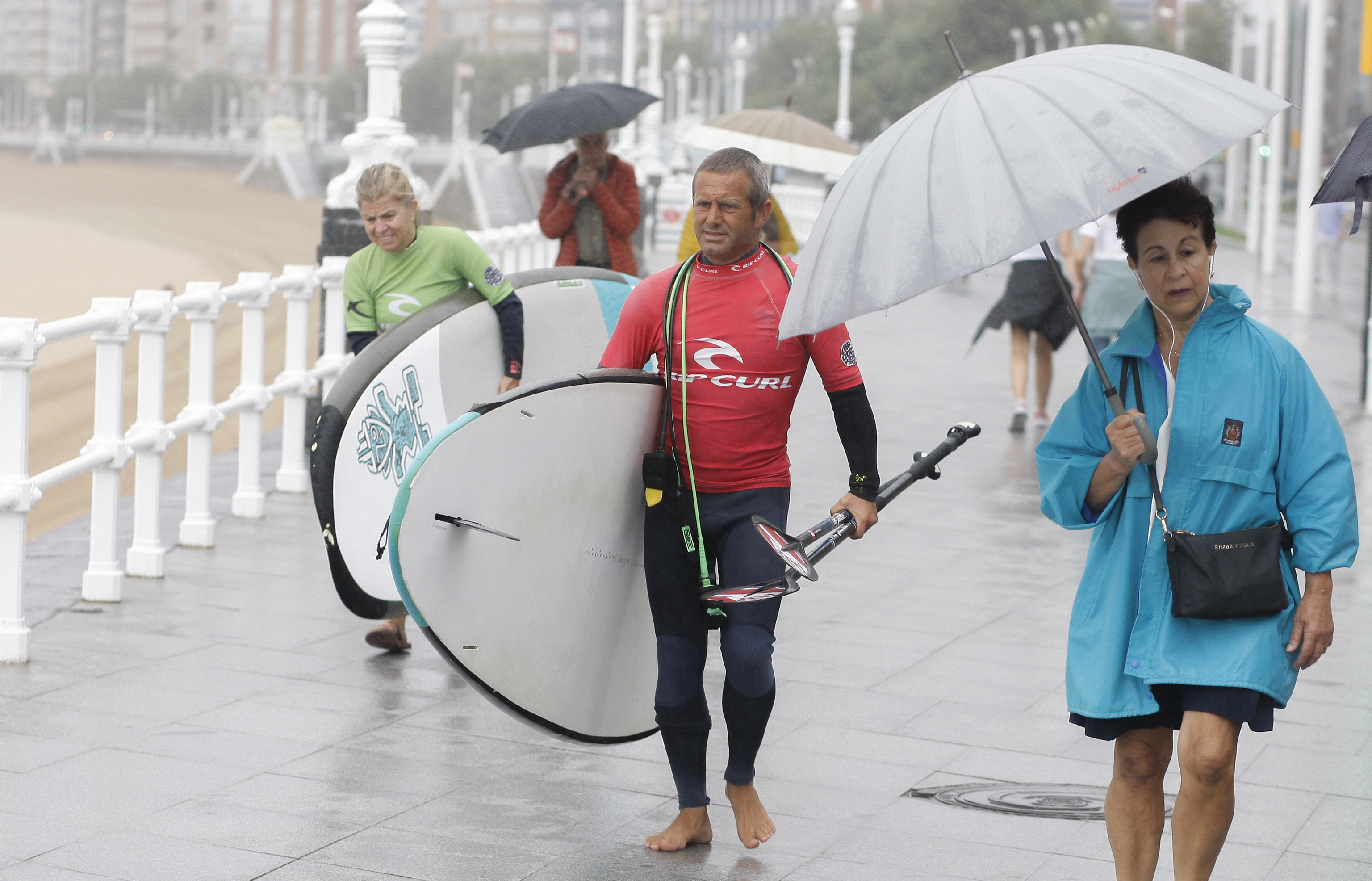 Unos surfistas bajo la lluvia en Gijn