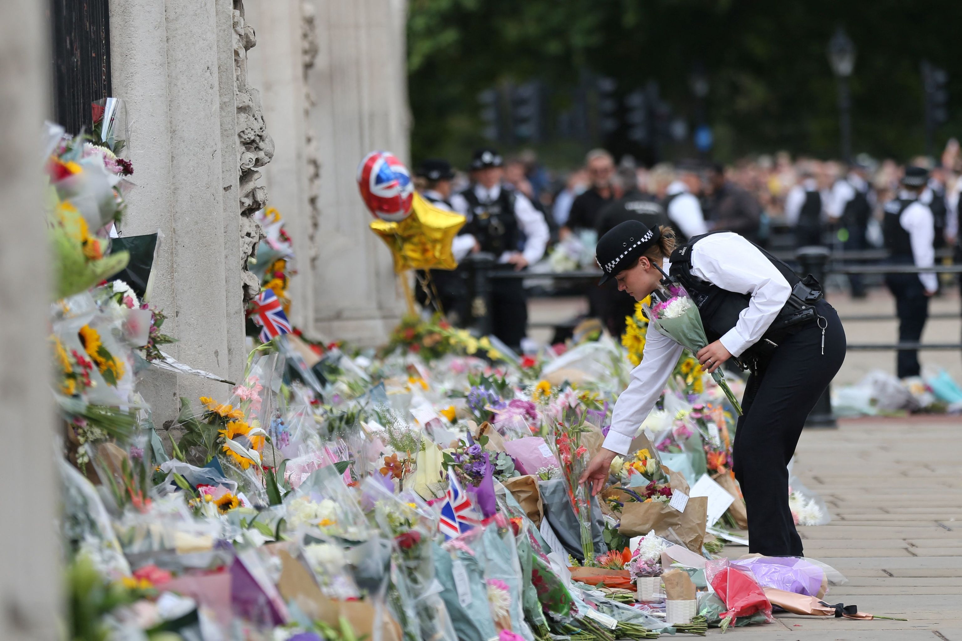 Una polica coloca flores en el Buckingham Palace