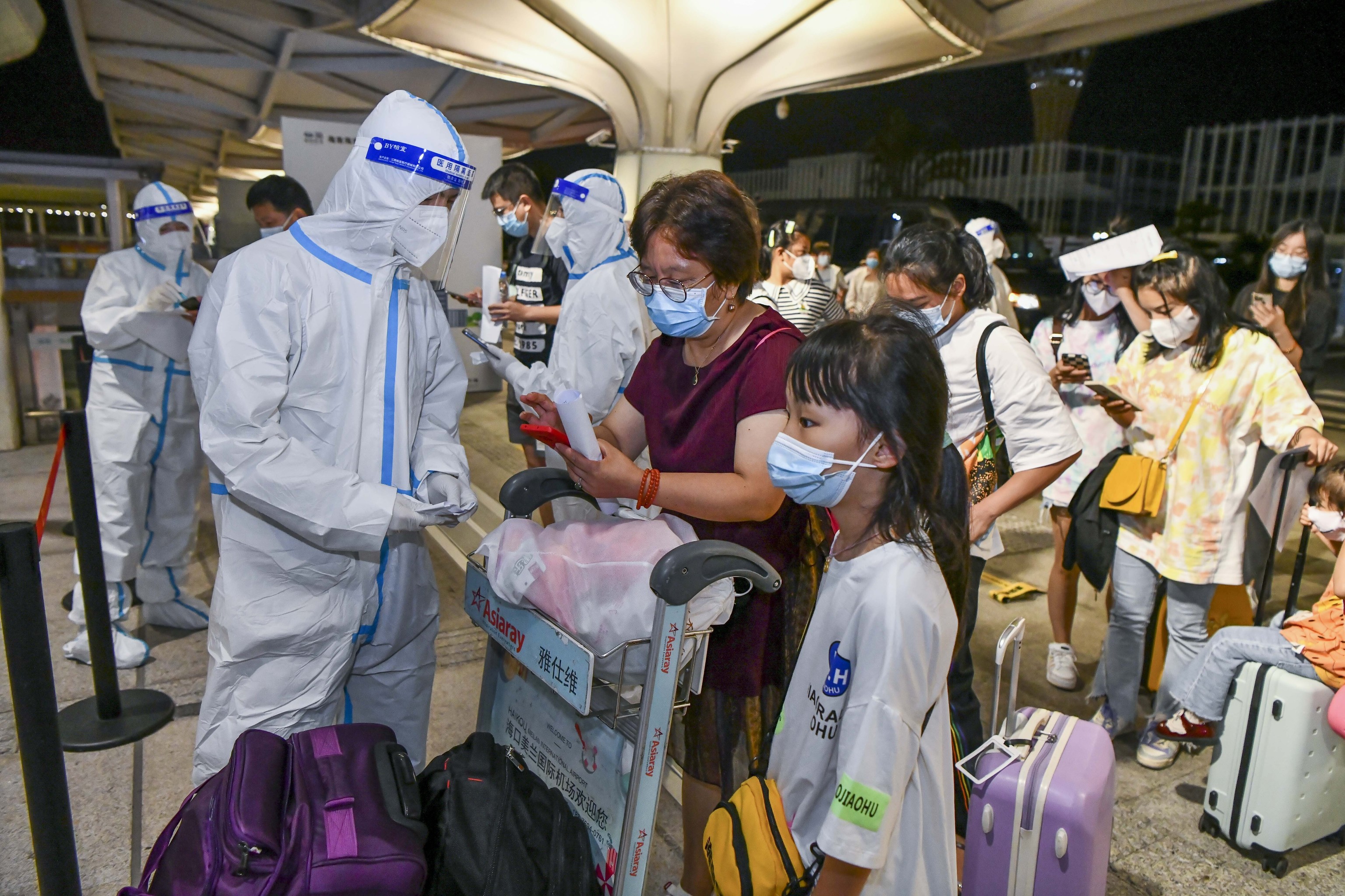 Miembros del personal verifican la información de las PCR en el Aeropuerto Internacional de Haikou Meilan.
