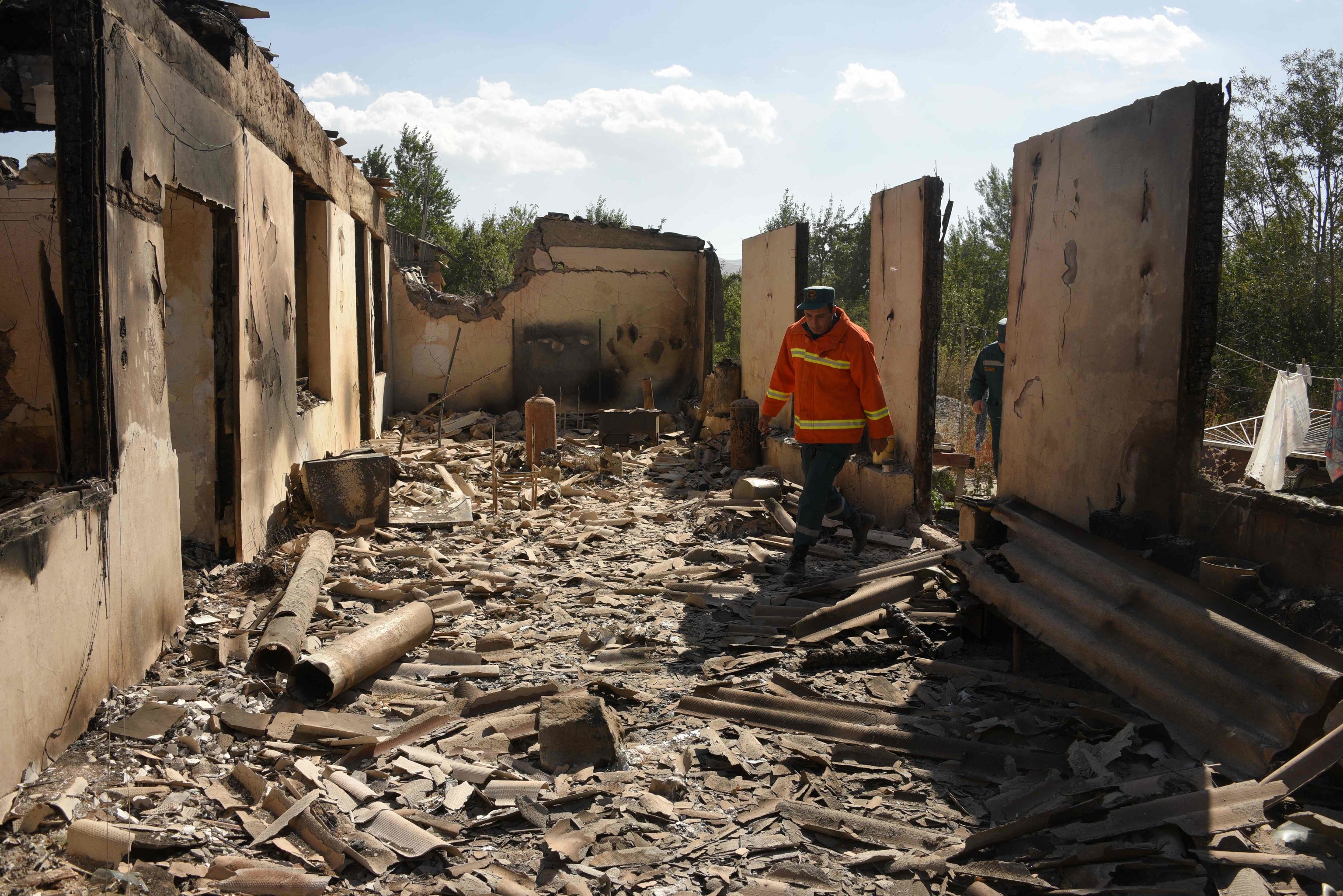 Bomberos en una casa destruida en un bombardeo.