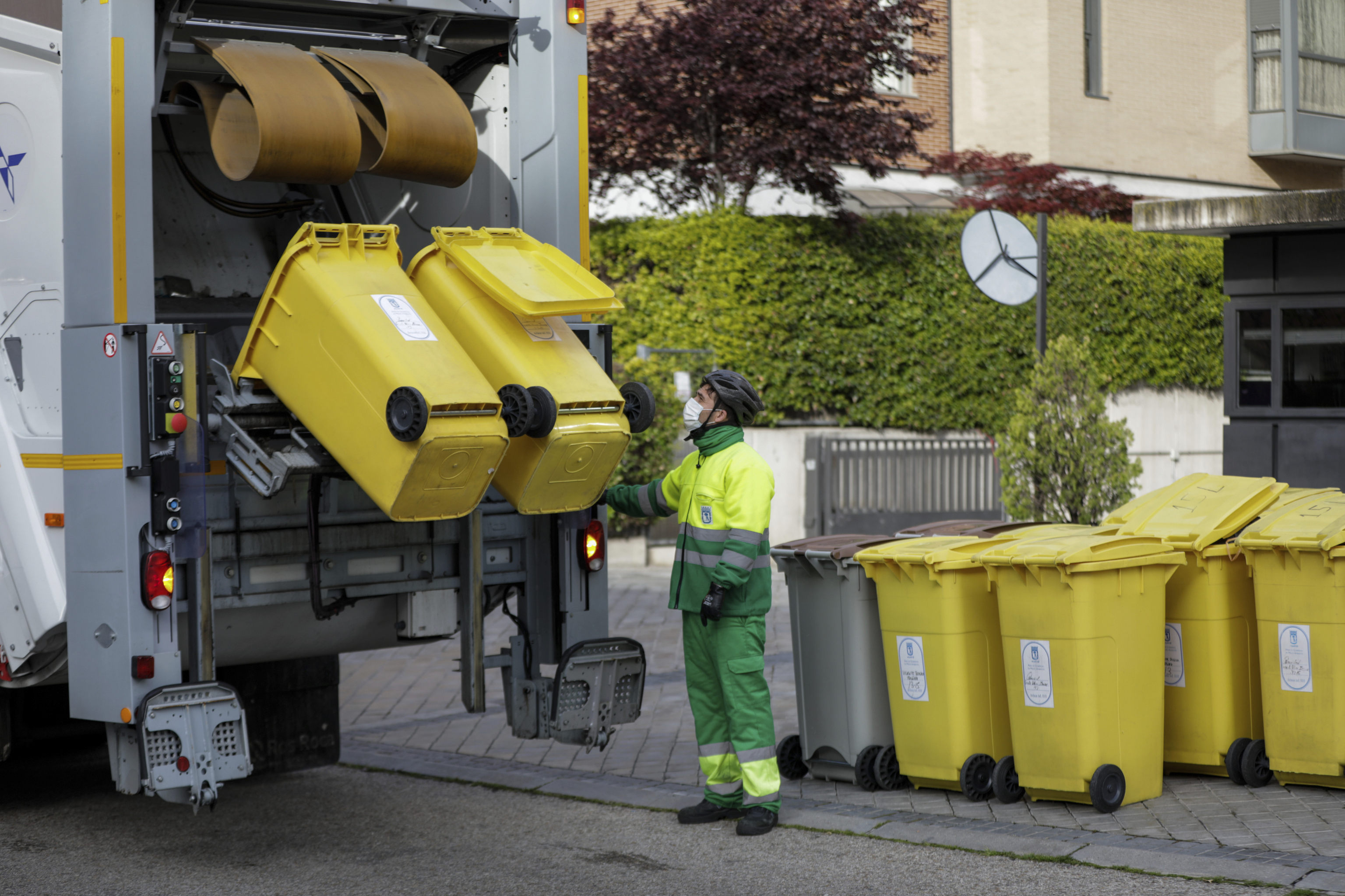 Un operario de recogida de residuos protegido con mascarilla observa cmo se tritura el contenido de cubos de basura amarillos destinados a envases en un camin de limpieza en una calle de la capital durante el da 33 del estado de alarma, en Madrid (Espaa)