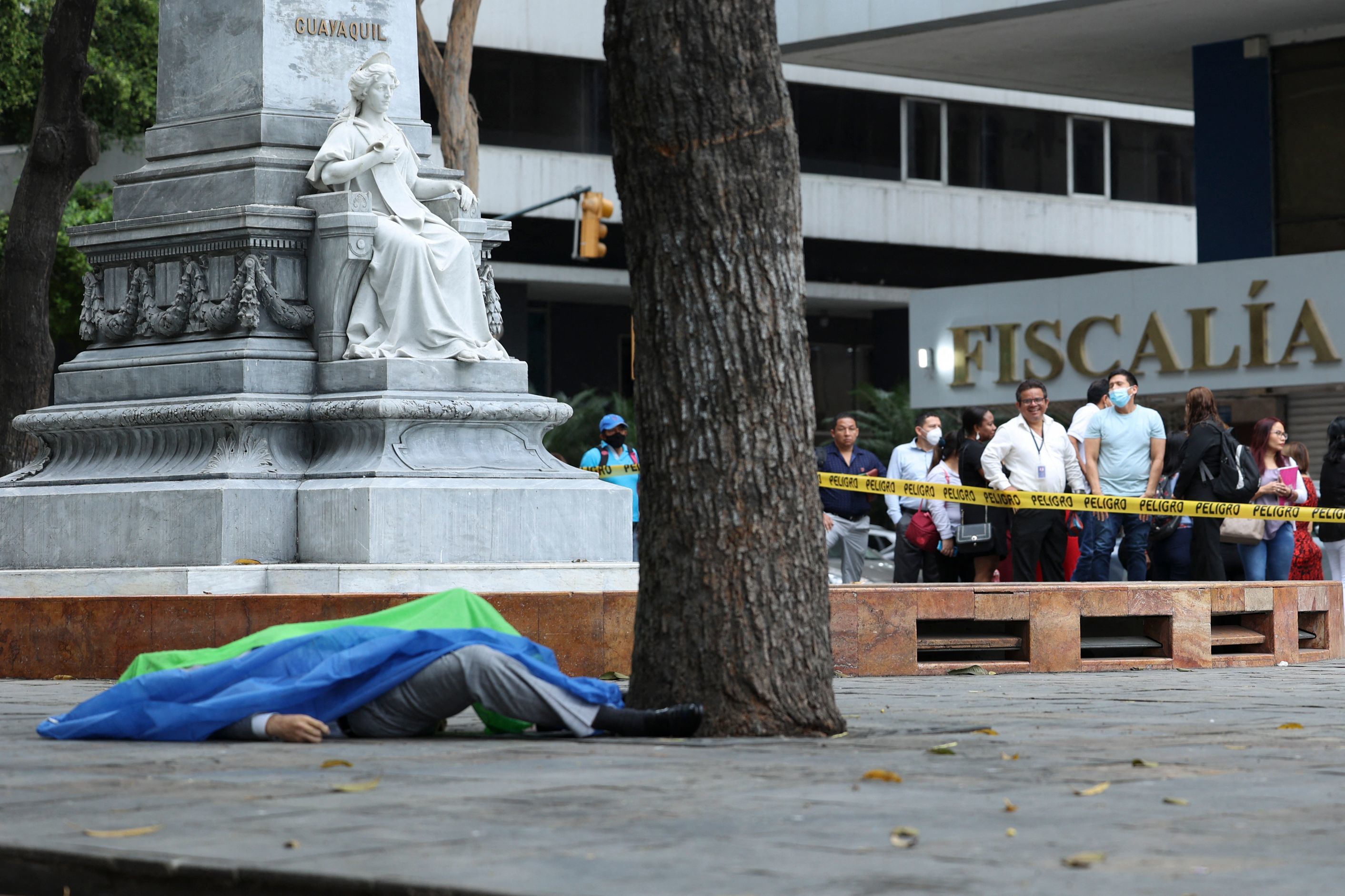El cadáver cubierto del fiscal ecuatoriano Edgar Escobar yace frente a la fiscalía en Guayaquil, Ecuador, el 19 de septiembre de 2022. - Un fiscal que investigaba los crímenes de odio y el feminicidio fue asesinado este lunes en las afueras de la Fiscalía ecuatoriana en Guayaquil, informó el organismo gubernamental.