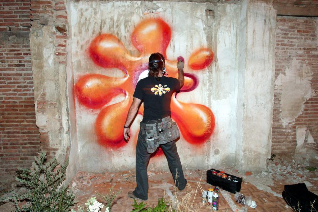 Un grafitero pinta un muro en Madrid.