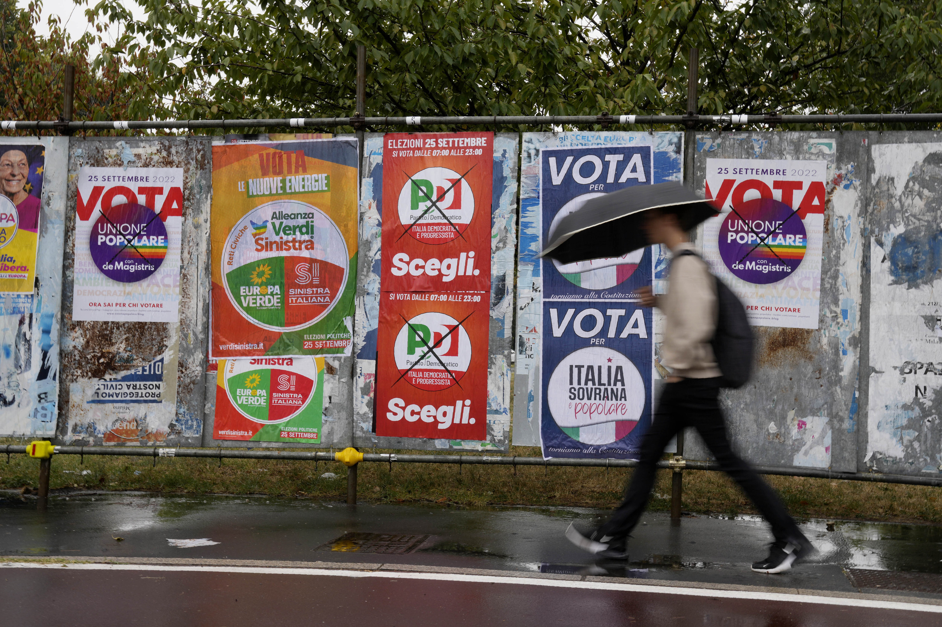 Un hombre camina por delante de vallas con propaganda electoral, en Milán.