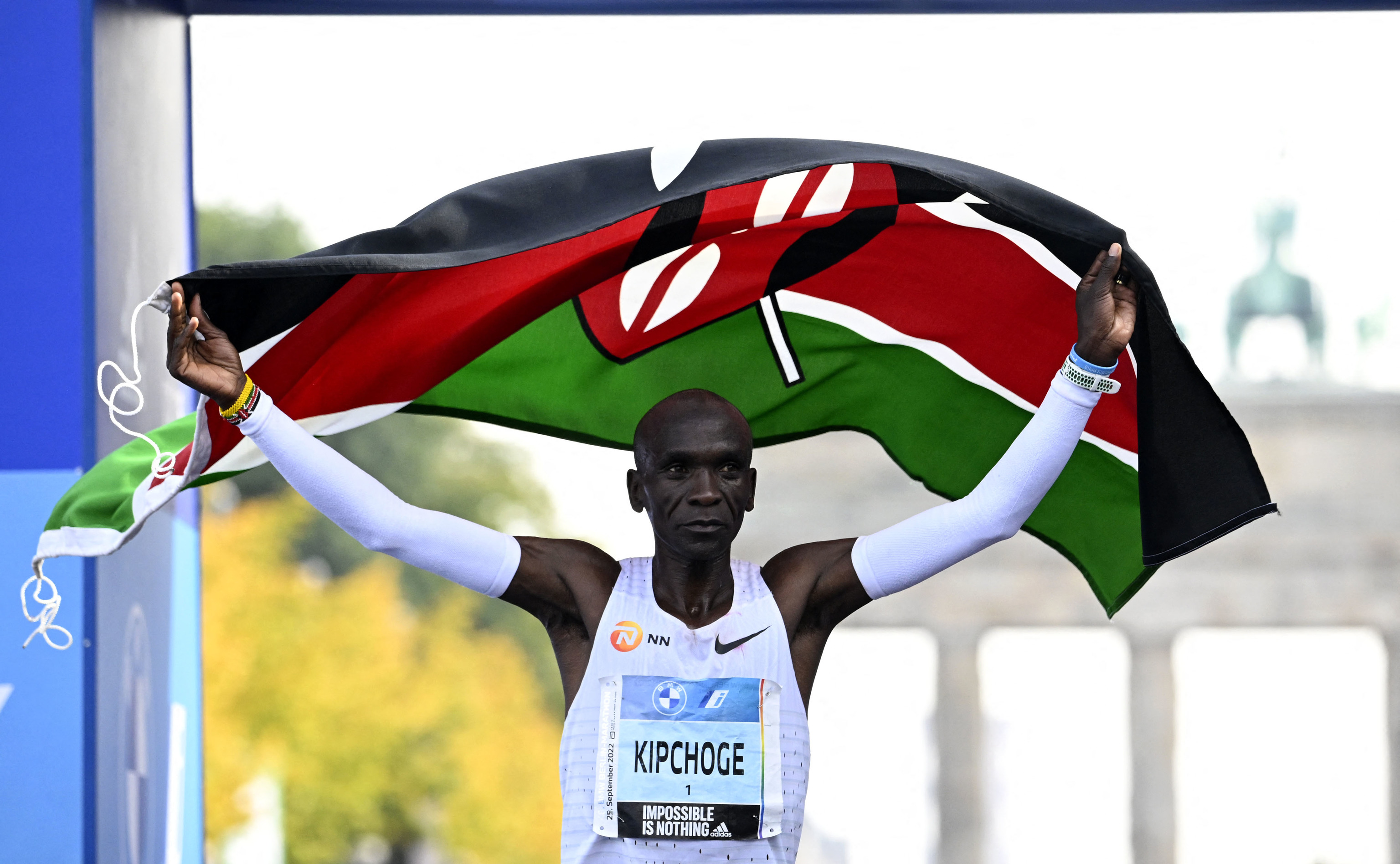 Kipchoge, al entrar en meta, con la bandera de Kenia