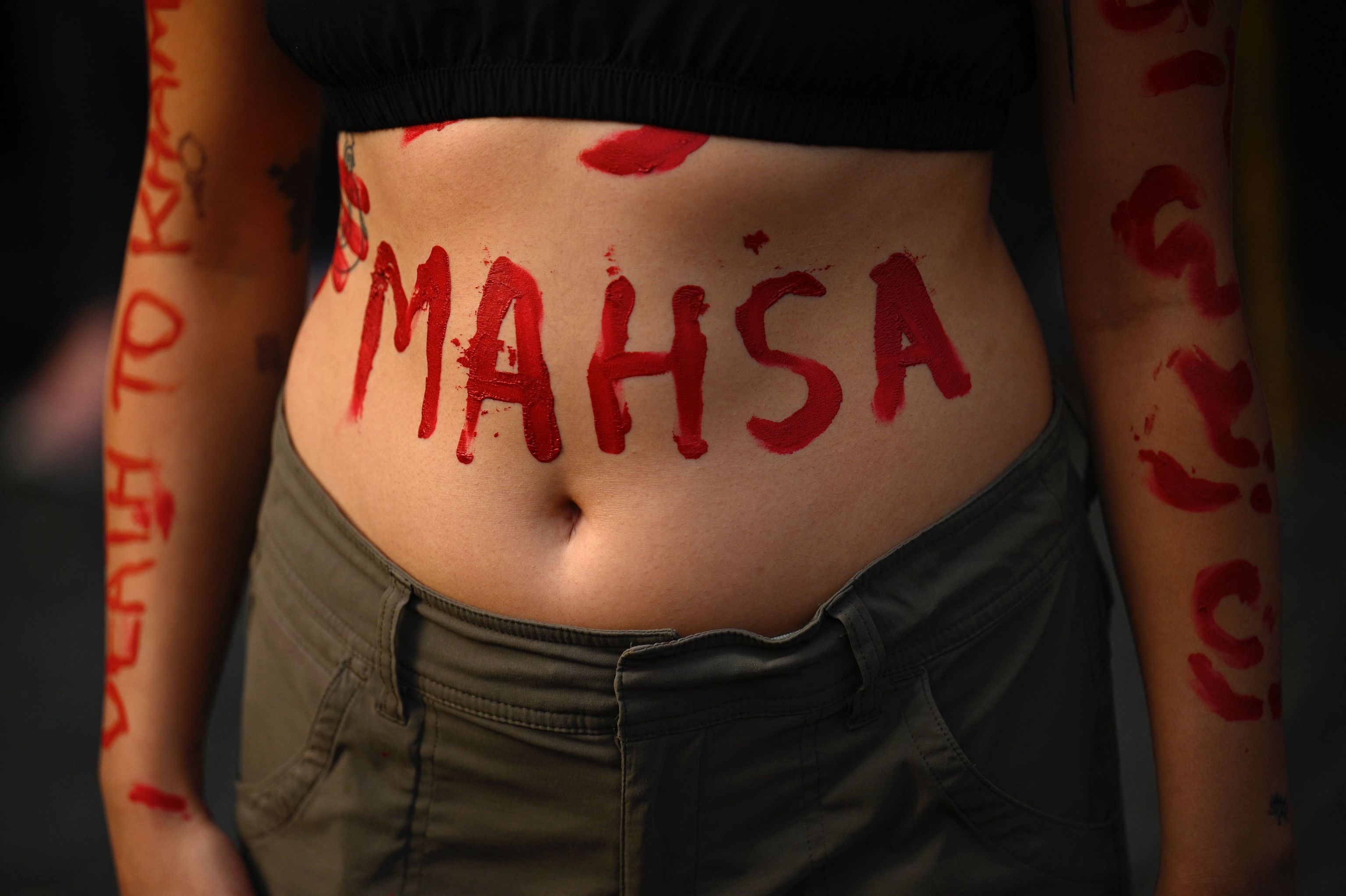 Una manifestante con el nombre de Mahsa pintado en su cuerpo.