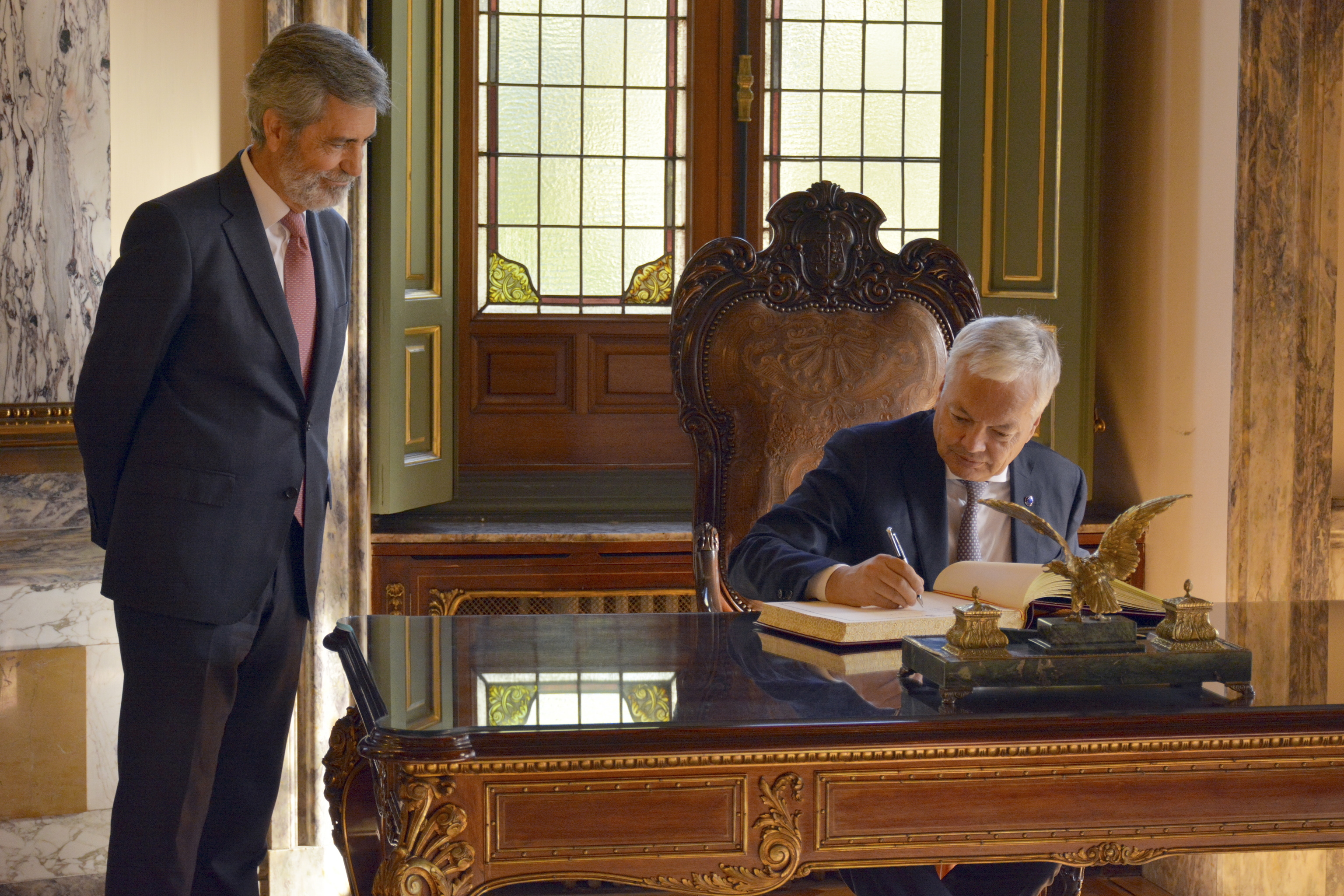 El comisario Didier Reynders firma en el libro de visitas durante el encuentro con el presidente del CGPJ, Carlos Lesmes.