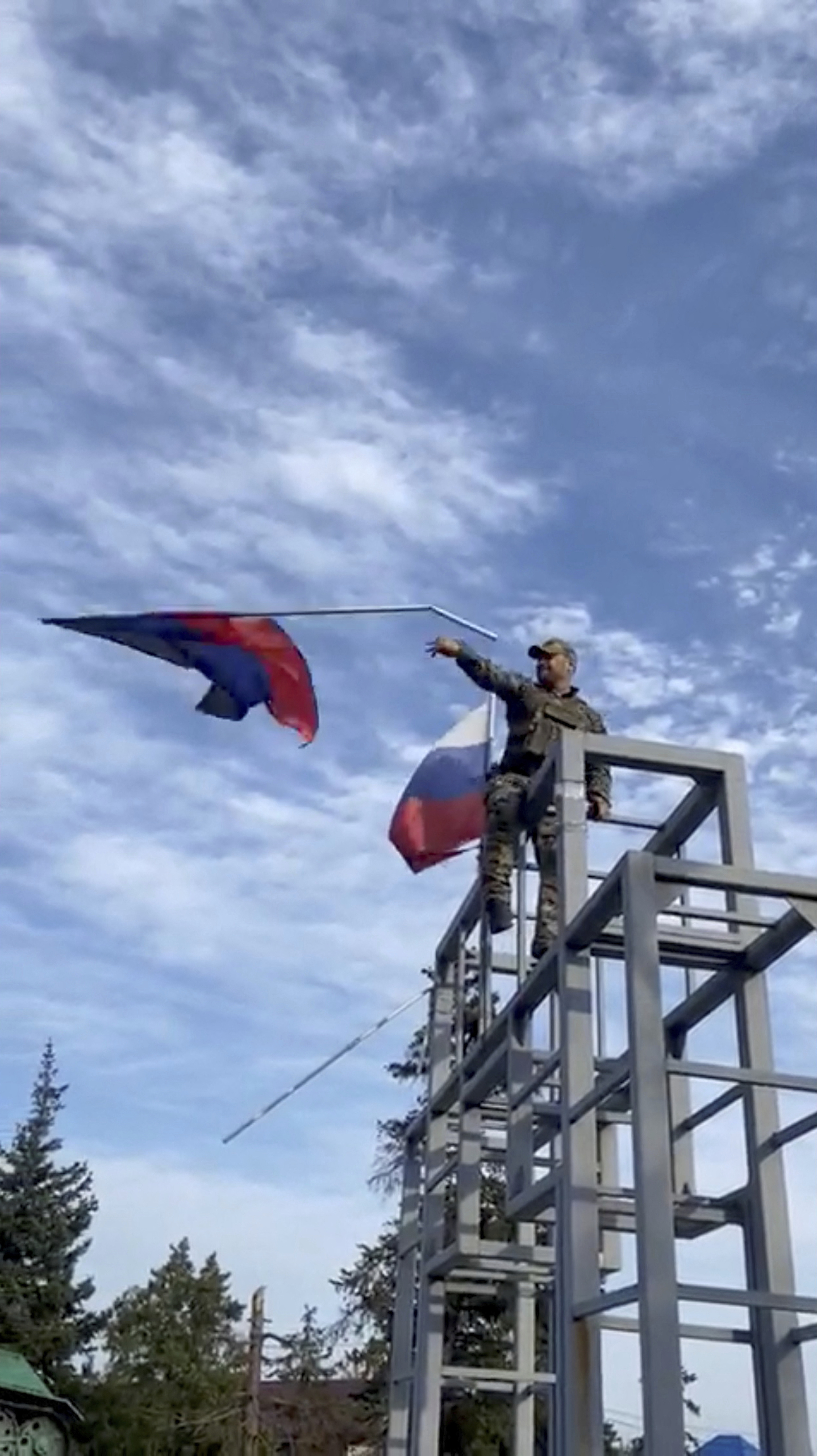 Un militar ucraniano quita la bandera de la pseudorrepública de Donetsk para colocar la Ucraniana, en Liman,