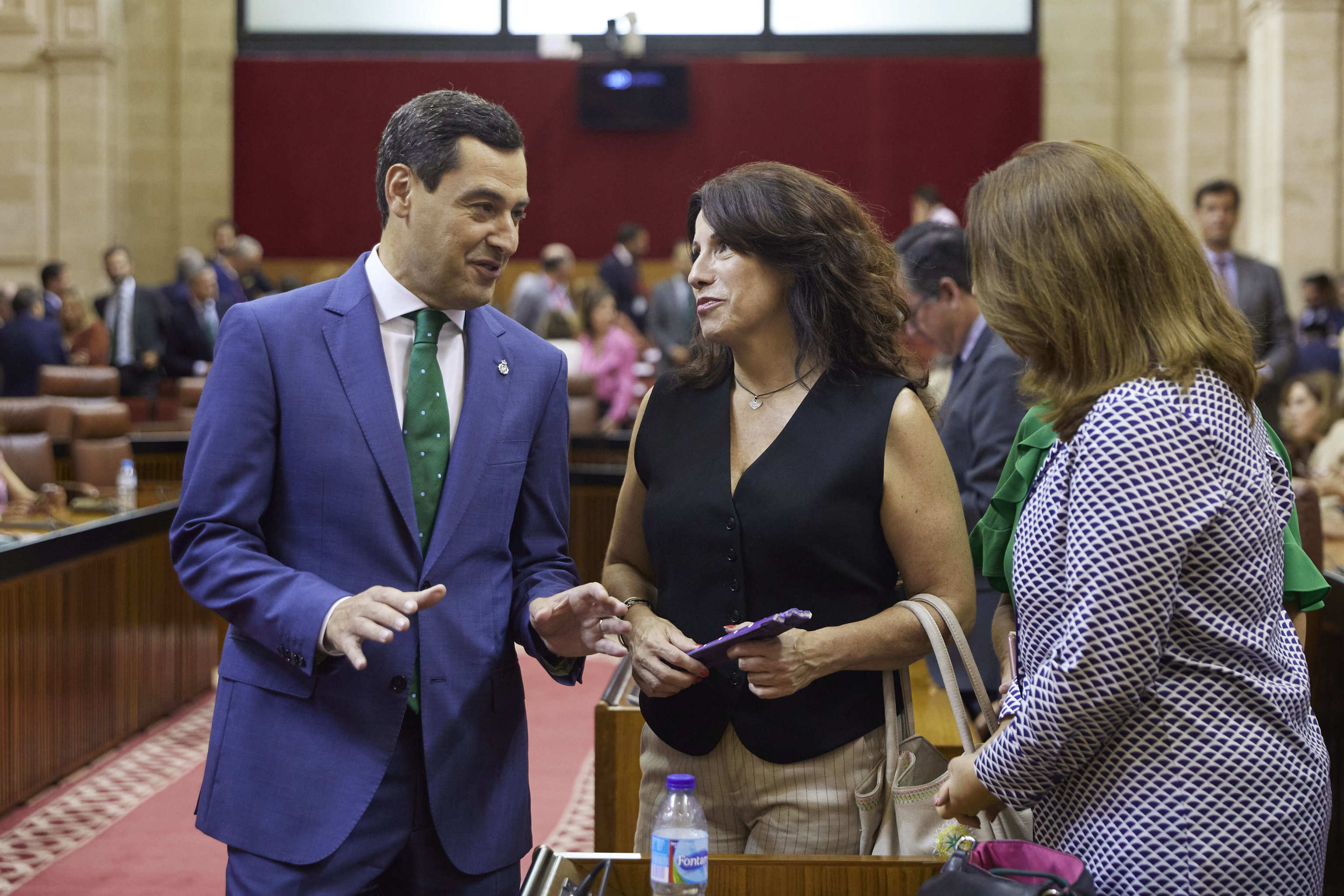 El presidente de la Junta, Juanma Moreno, conversa con la ex consejera de Igualdad, Roco Ruiz, en un pleno del Parlamento.