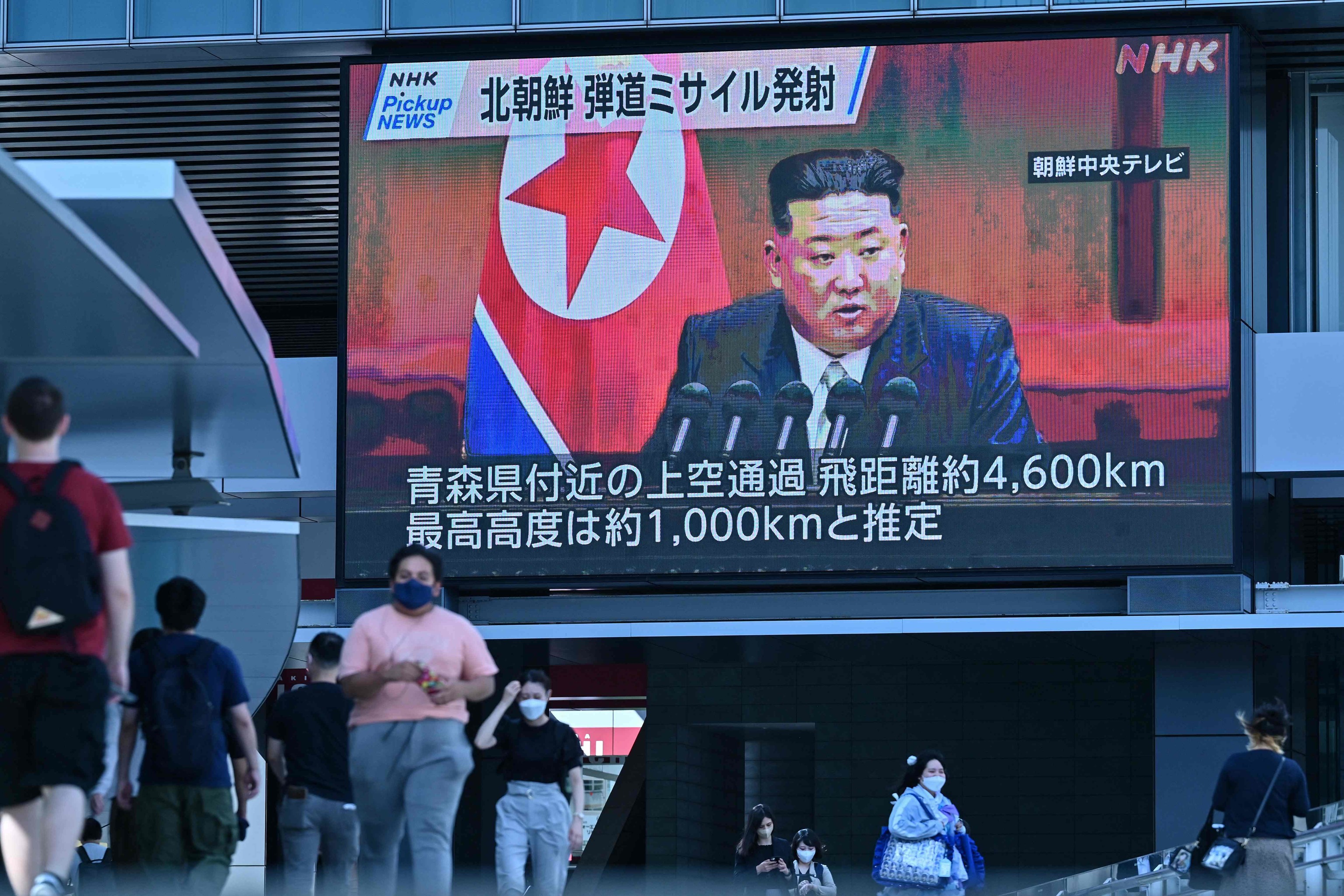 Peatones en Tokio caminan bajo una gran pantalla que muestra imgenes de Kim Jong-un.