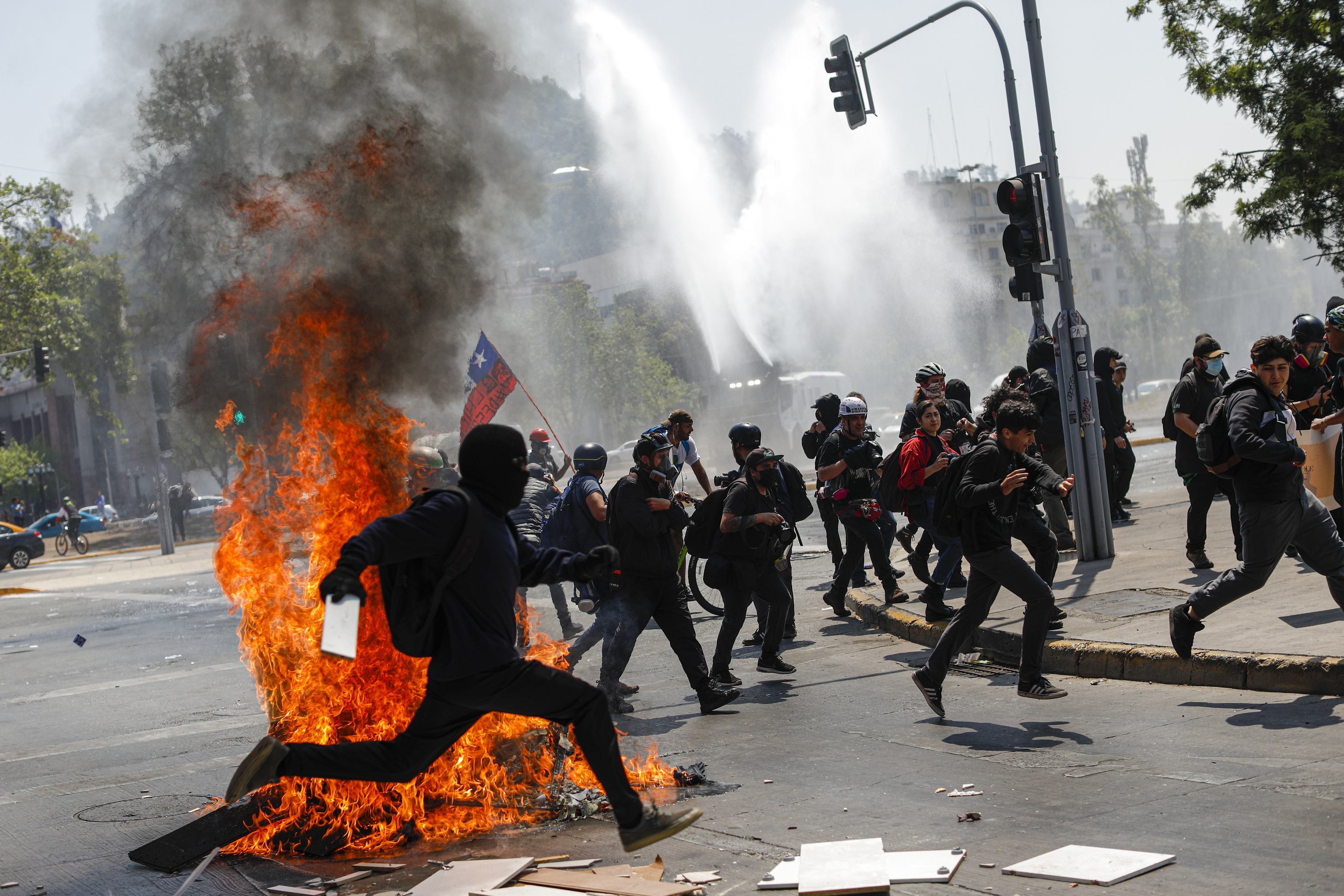 Manifestantes huyen de agentes policiales antidisturbios, en Santiago este martes.