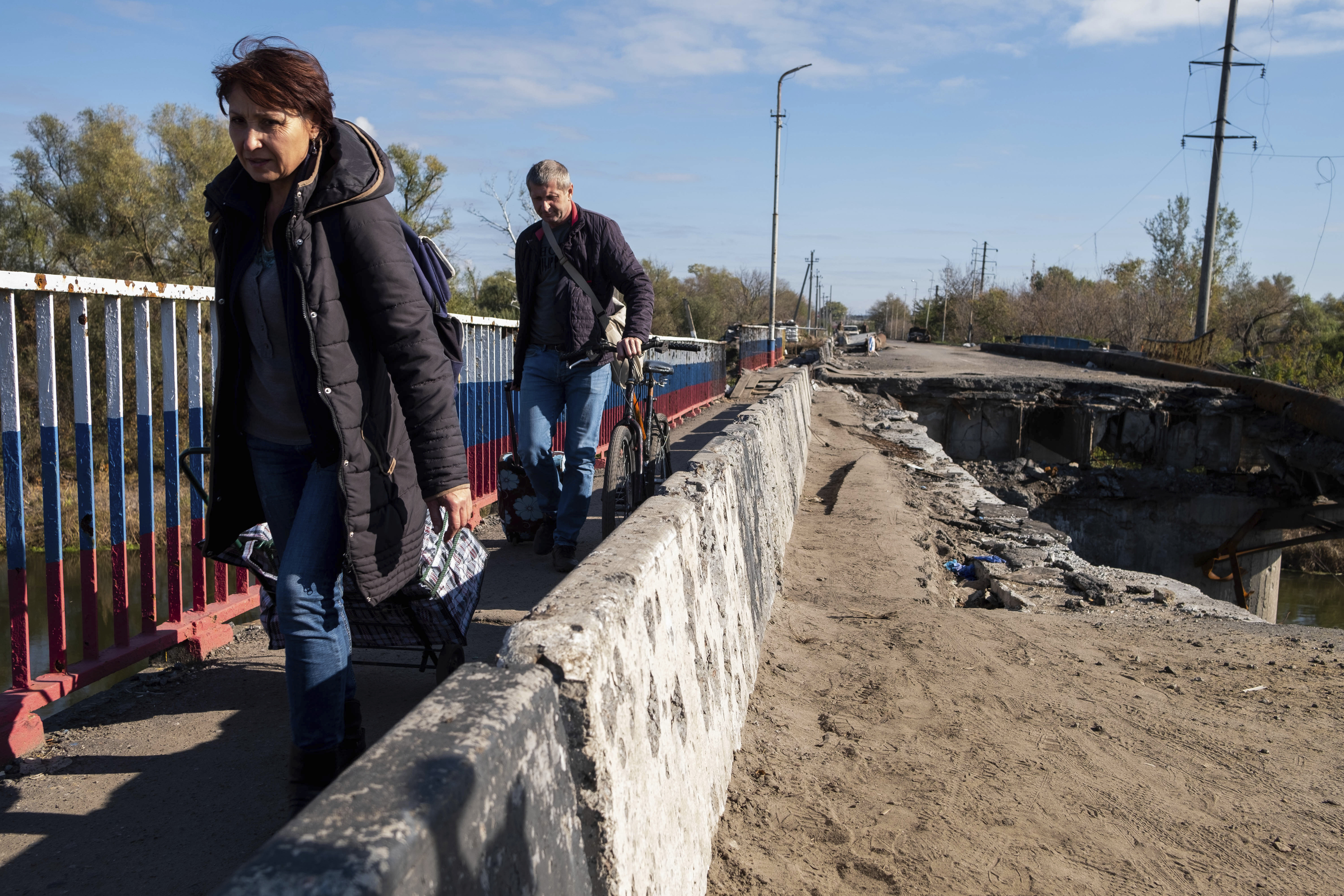 Civiles ucranianos huyen en bicicleta de la cercana batalla por Svatove cruzando el puente de Kupiansk.