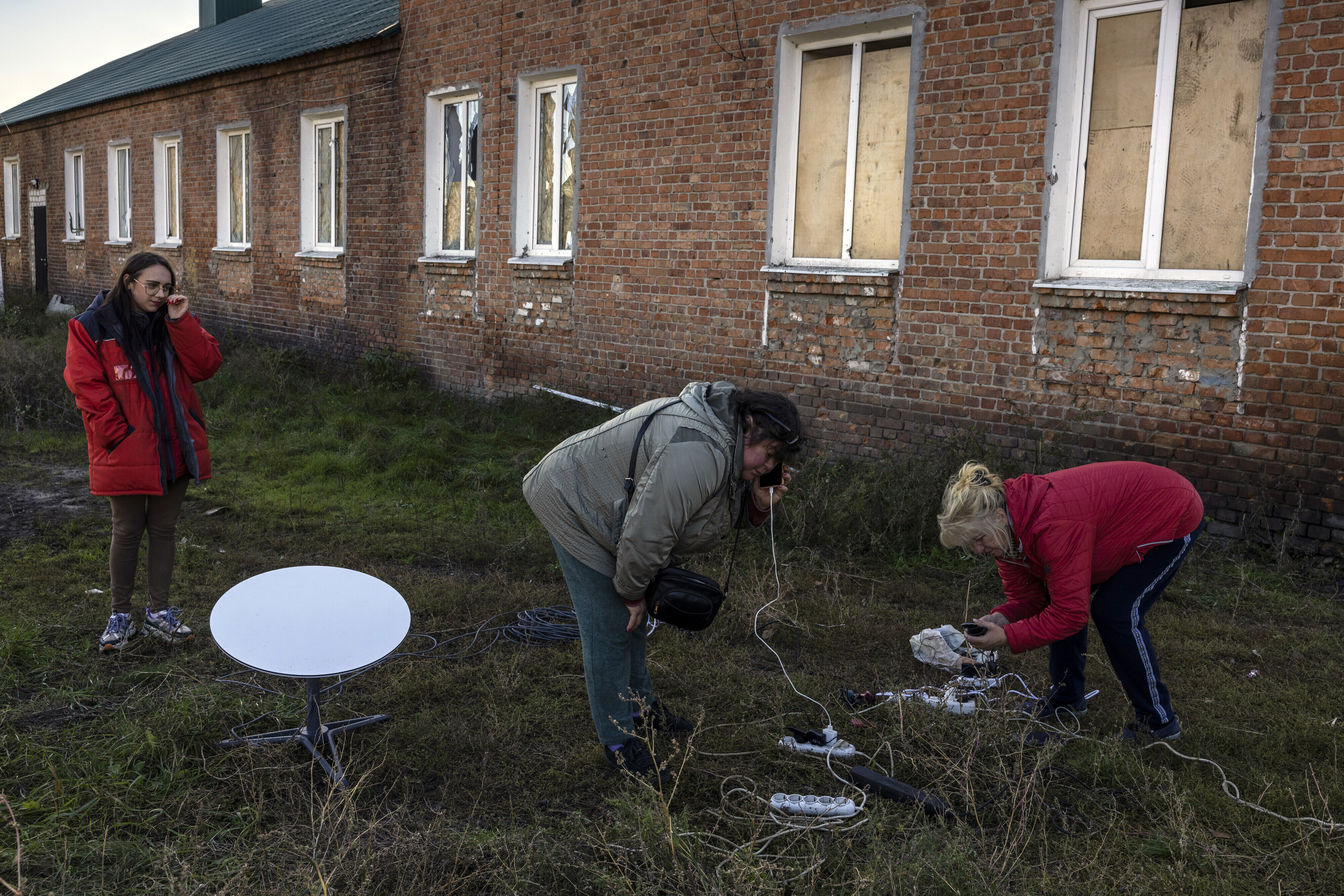 Varias mujeres se renen alrededor de una antena parablica para cargar sus telfonos en Staryi Saltiv, este lunes.