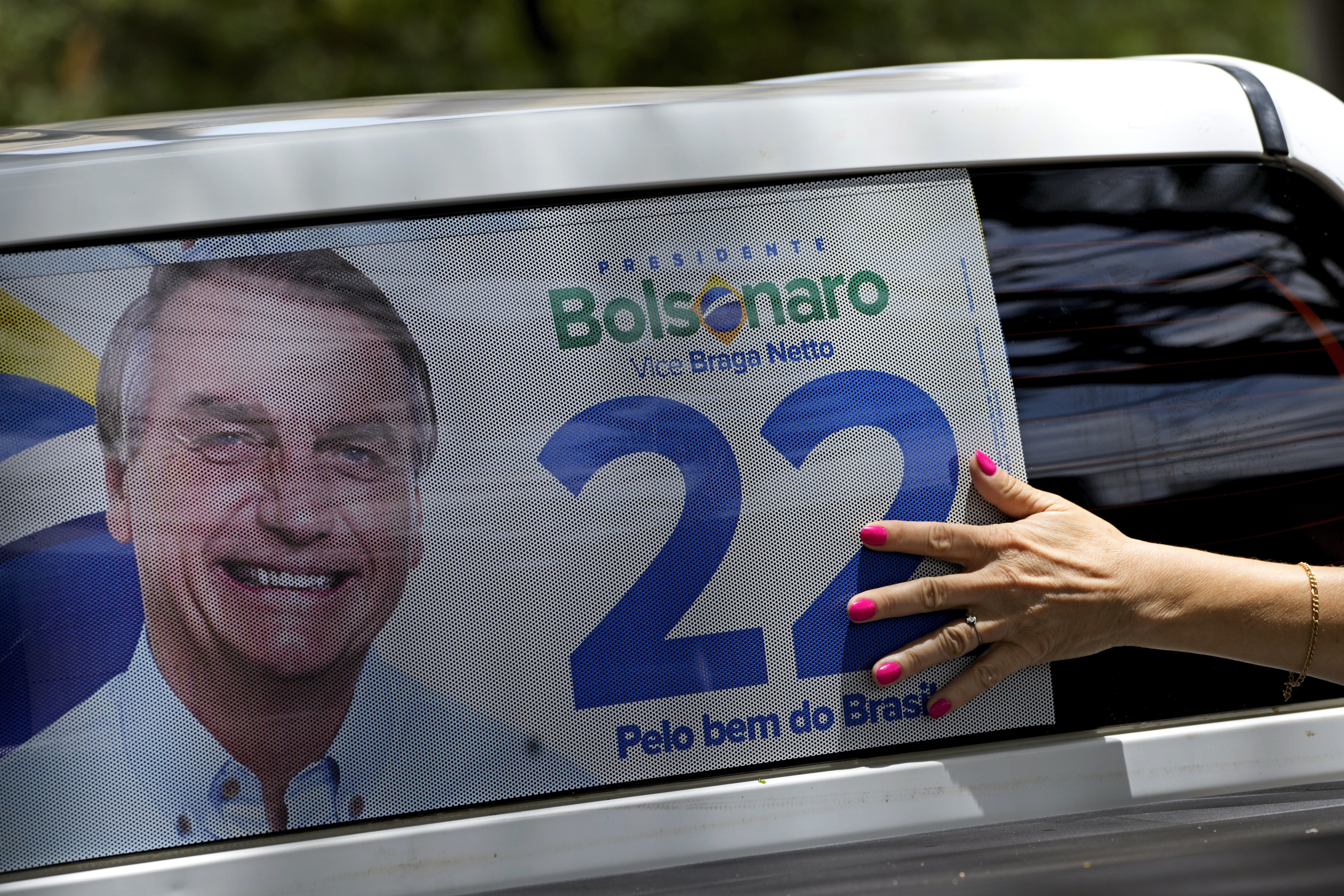 Un partidario de Bolsonaro pone un cartel electoral en un vehículo