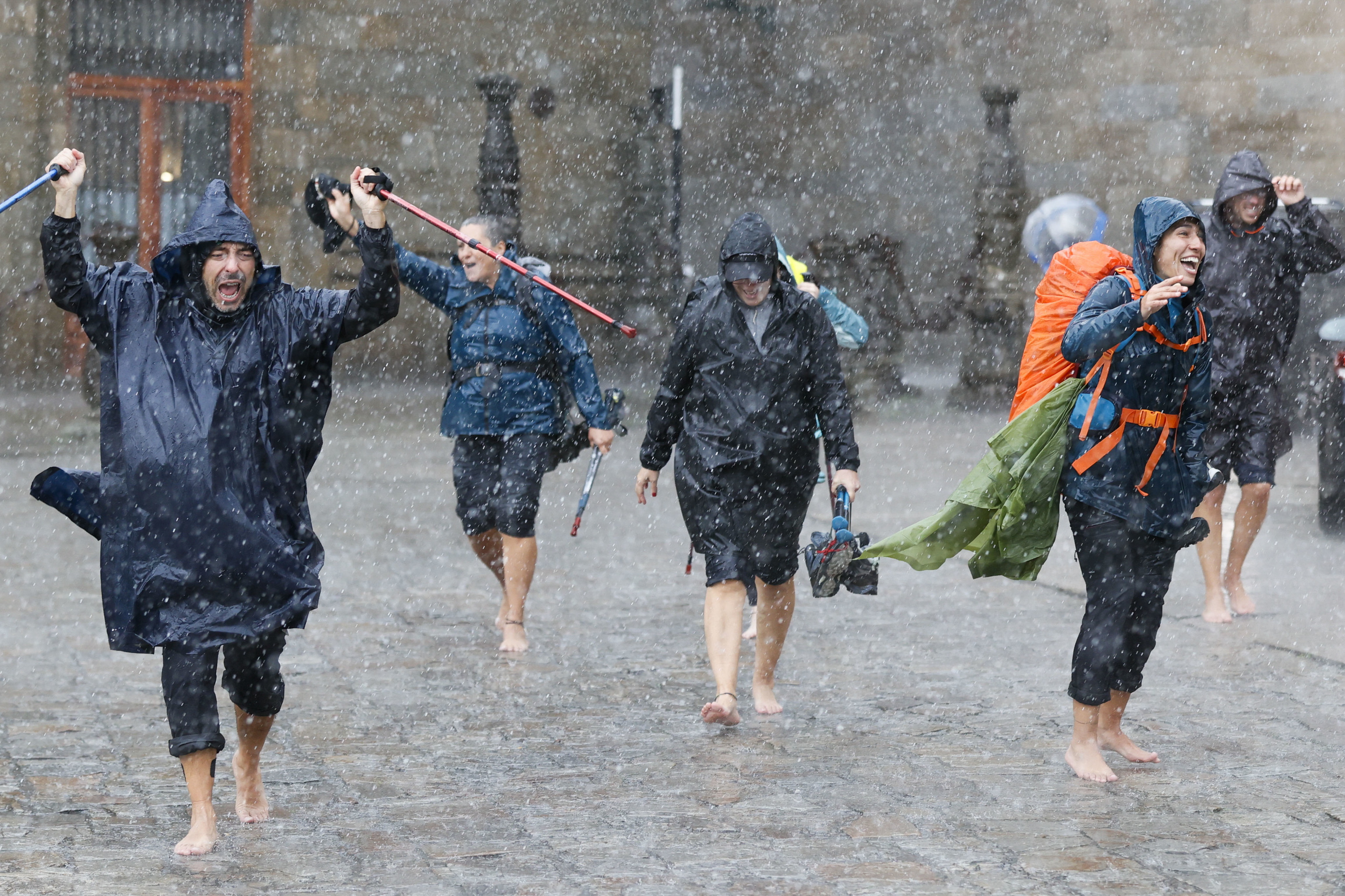 Un grupo de peregrinos termina bajo la lluvia el camino de Santiago.