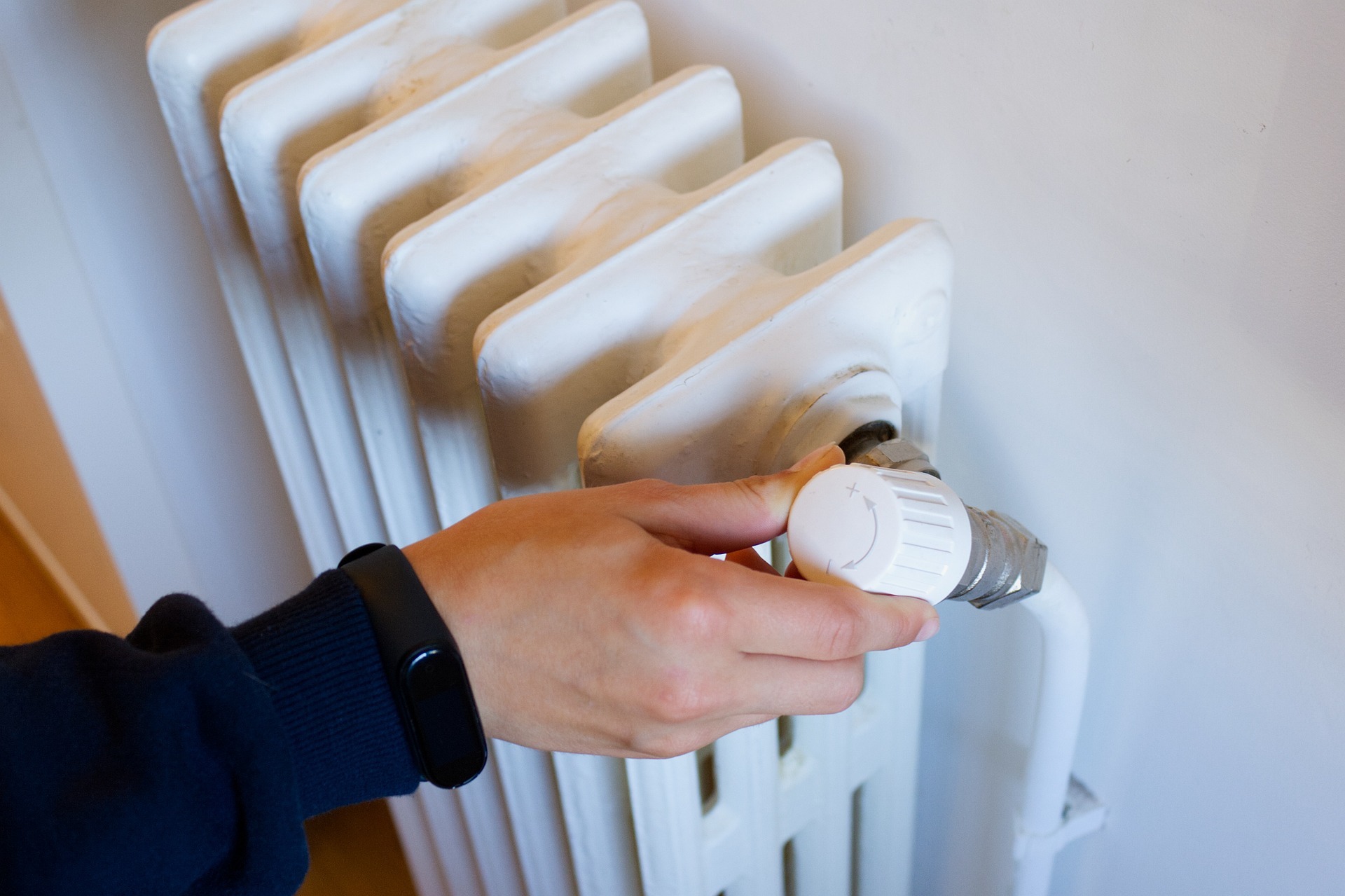 Una persona, regulando la temperatura de un radiador de calefaccin.