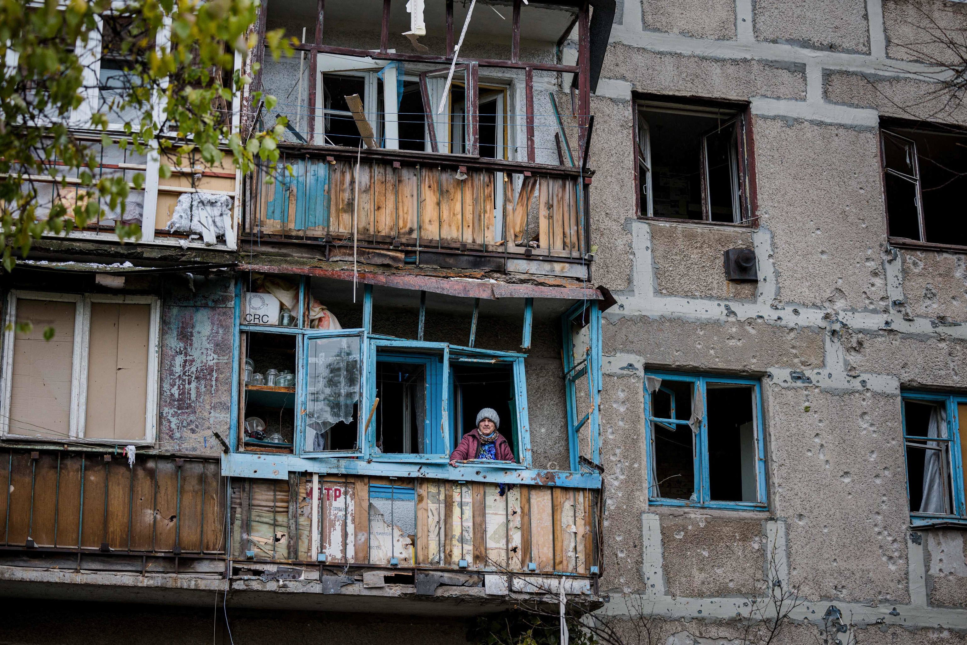 Una anciana se asoma al balcón de su edificio destrozado, en Bajmut.