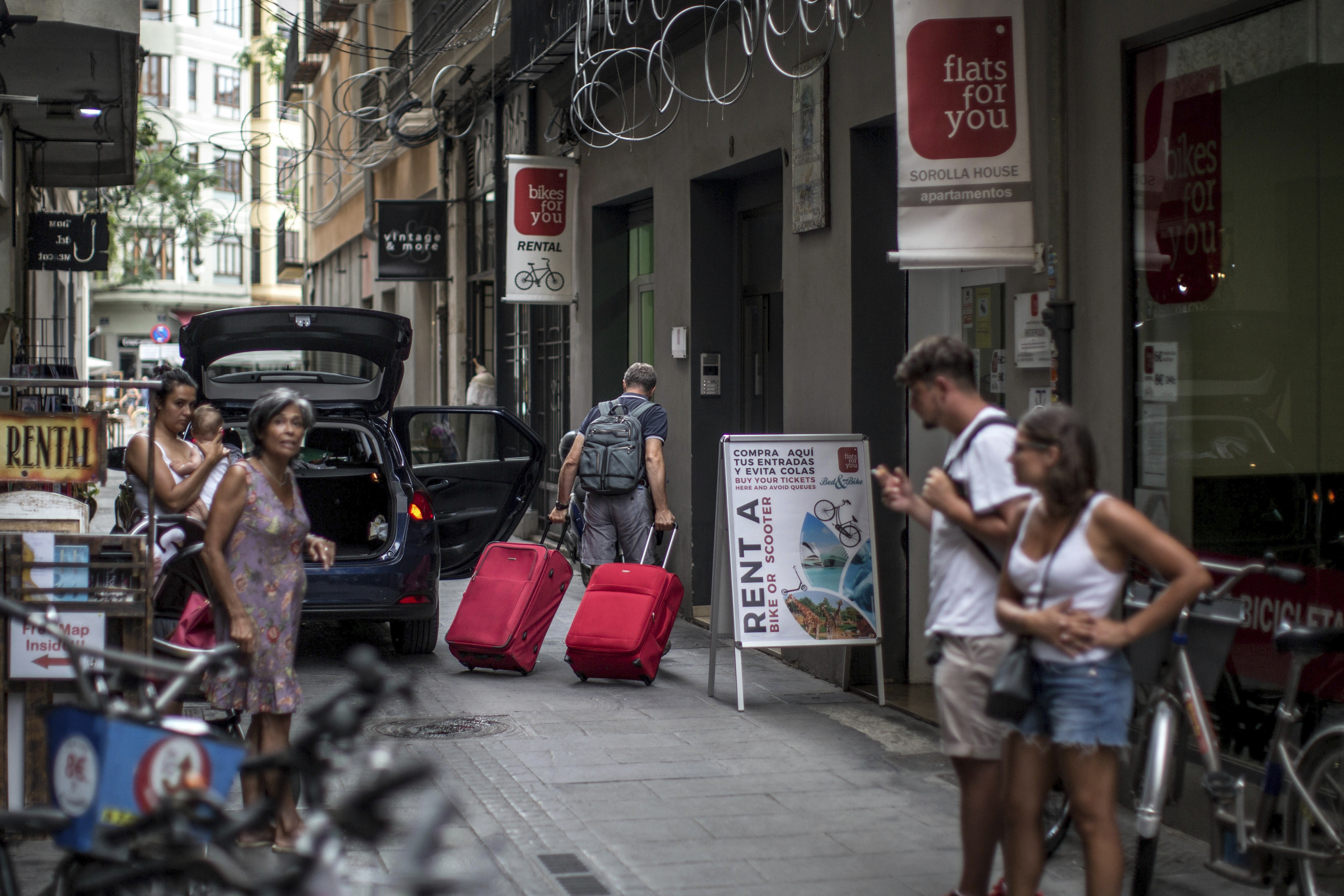 Un turista carga con maletas hacia un apartamento turstico en el centro de Valencia.
