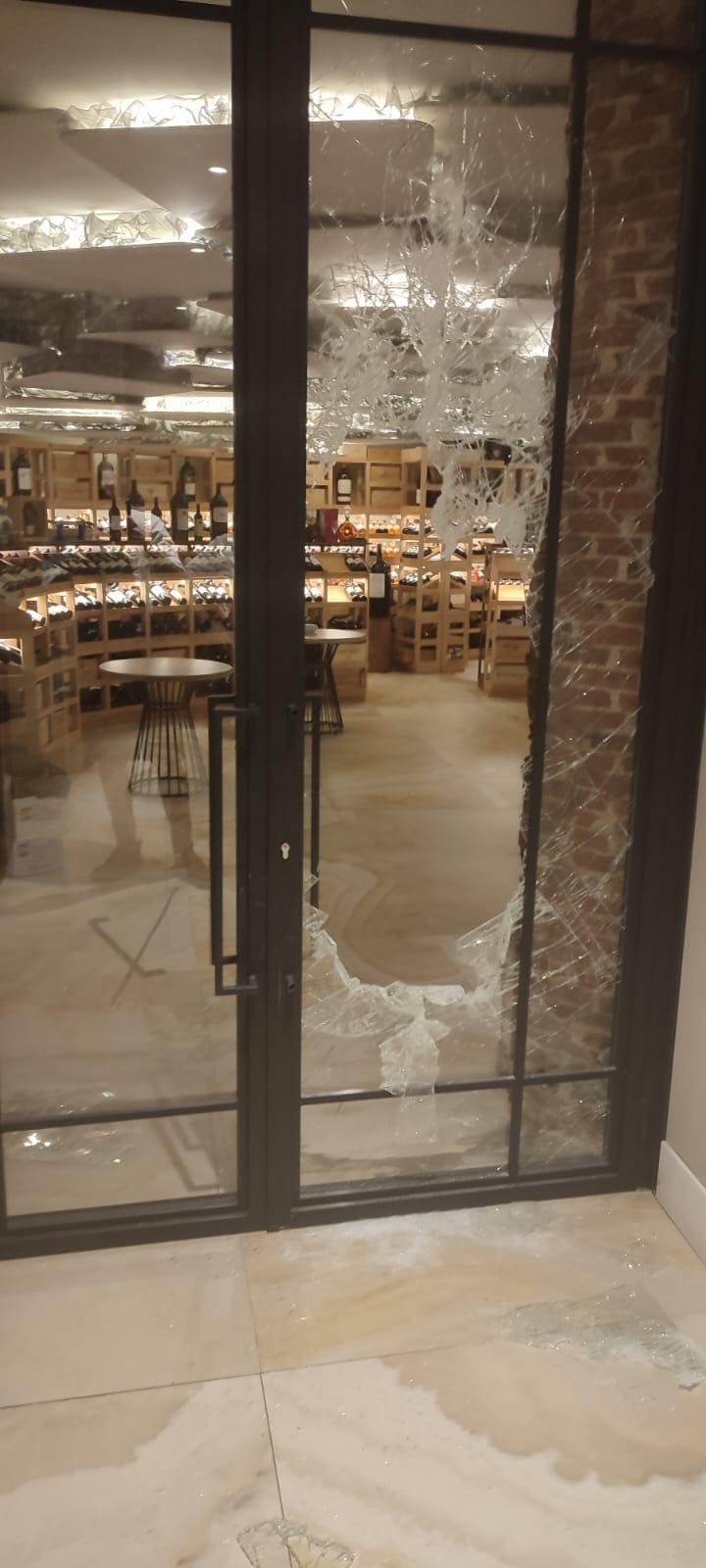 Puerta de cristal fracturada que da acceso a la bodega del restaurante Coque