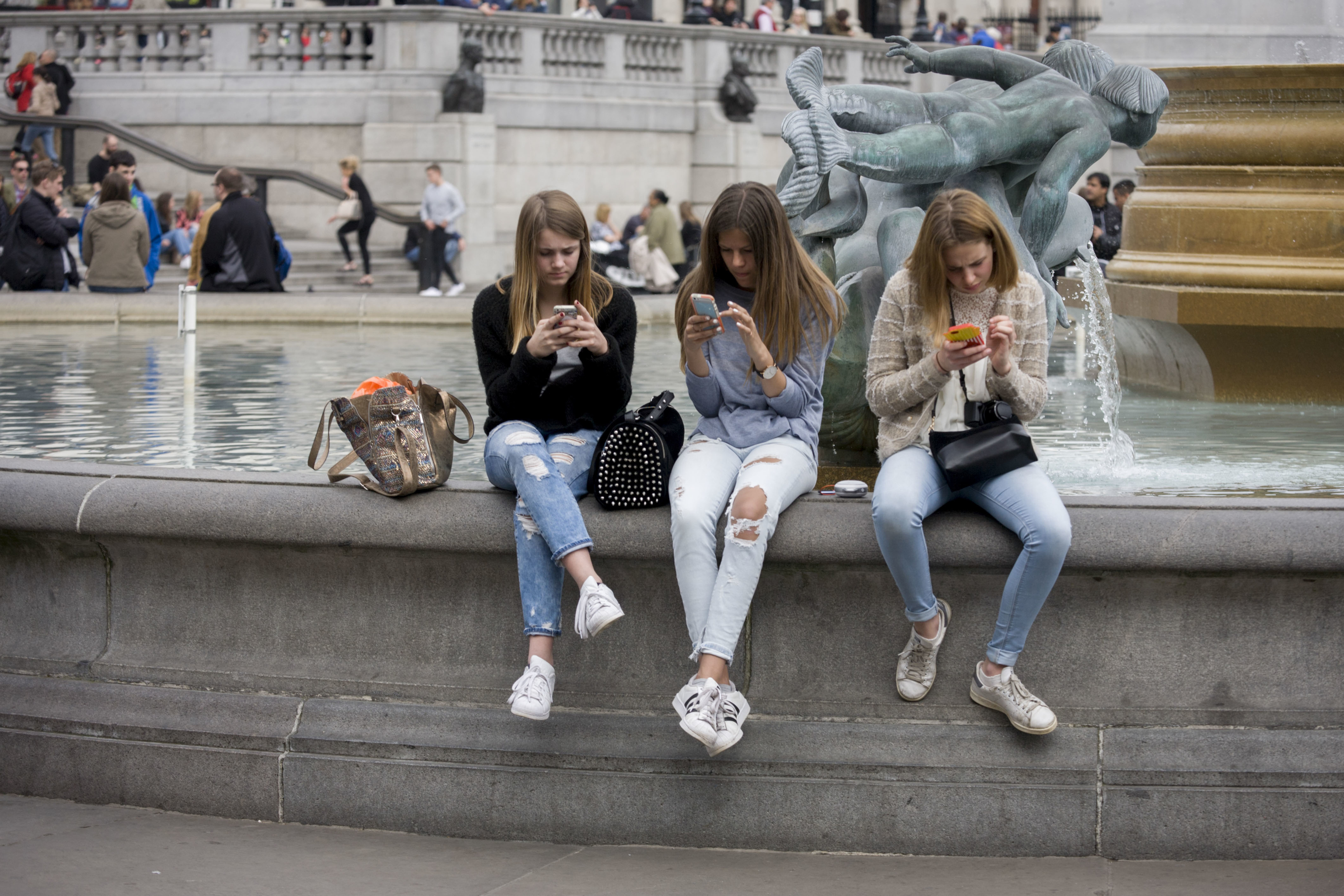 Tres jóvenes miran sus teléfonos móviles