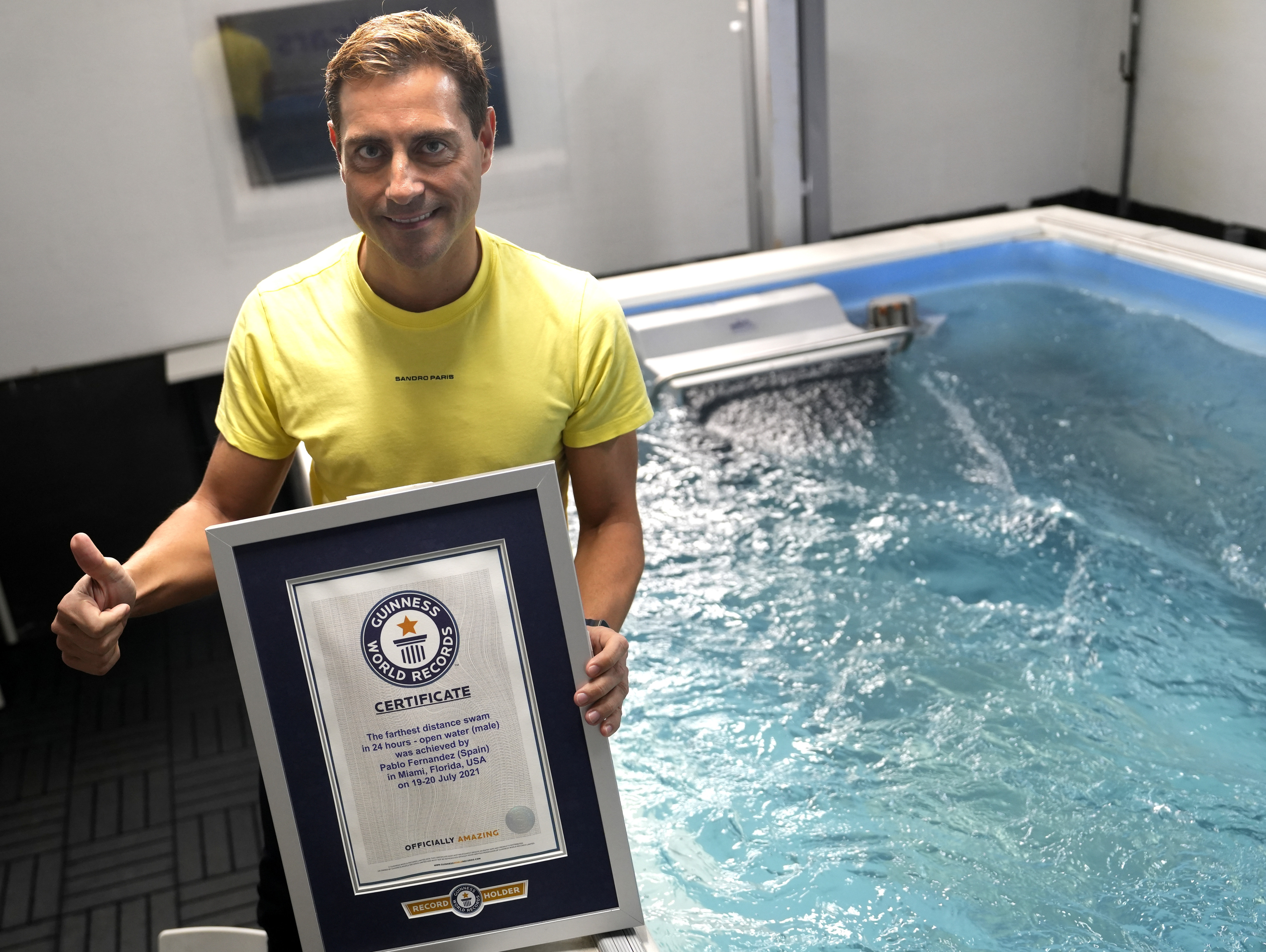 Pablo Fernndez sostiene en la piscina de su empresa uno de los certificados de rcords Guinness de natacin que tiene