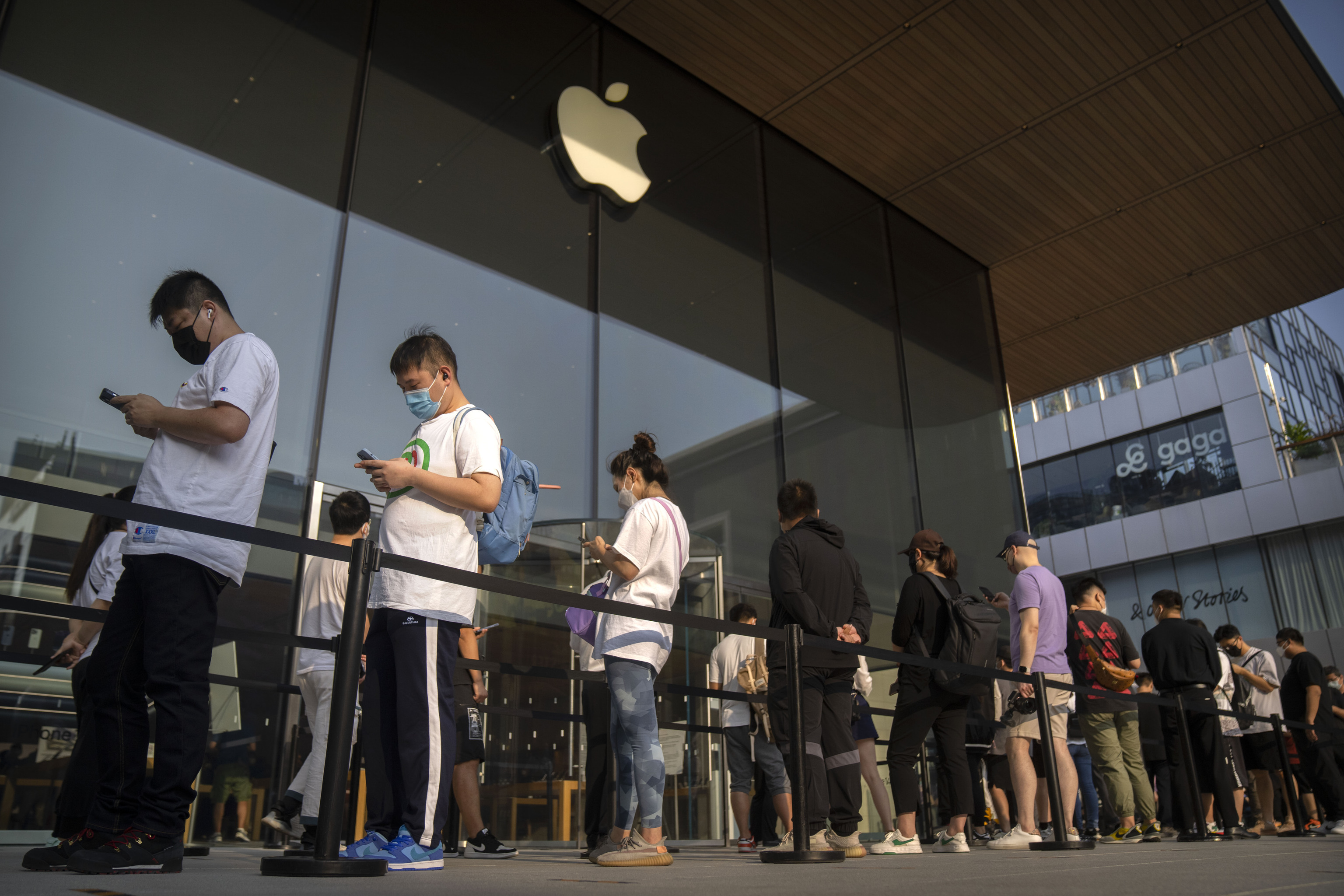 Varios clientes hacen cola frente a una tienda de Apple en Pekín.