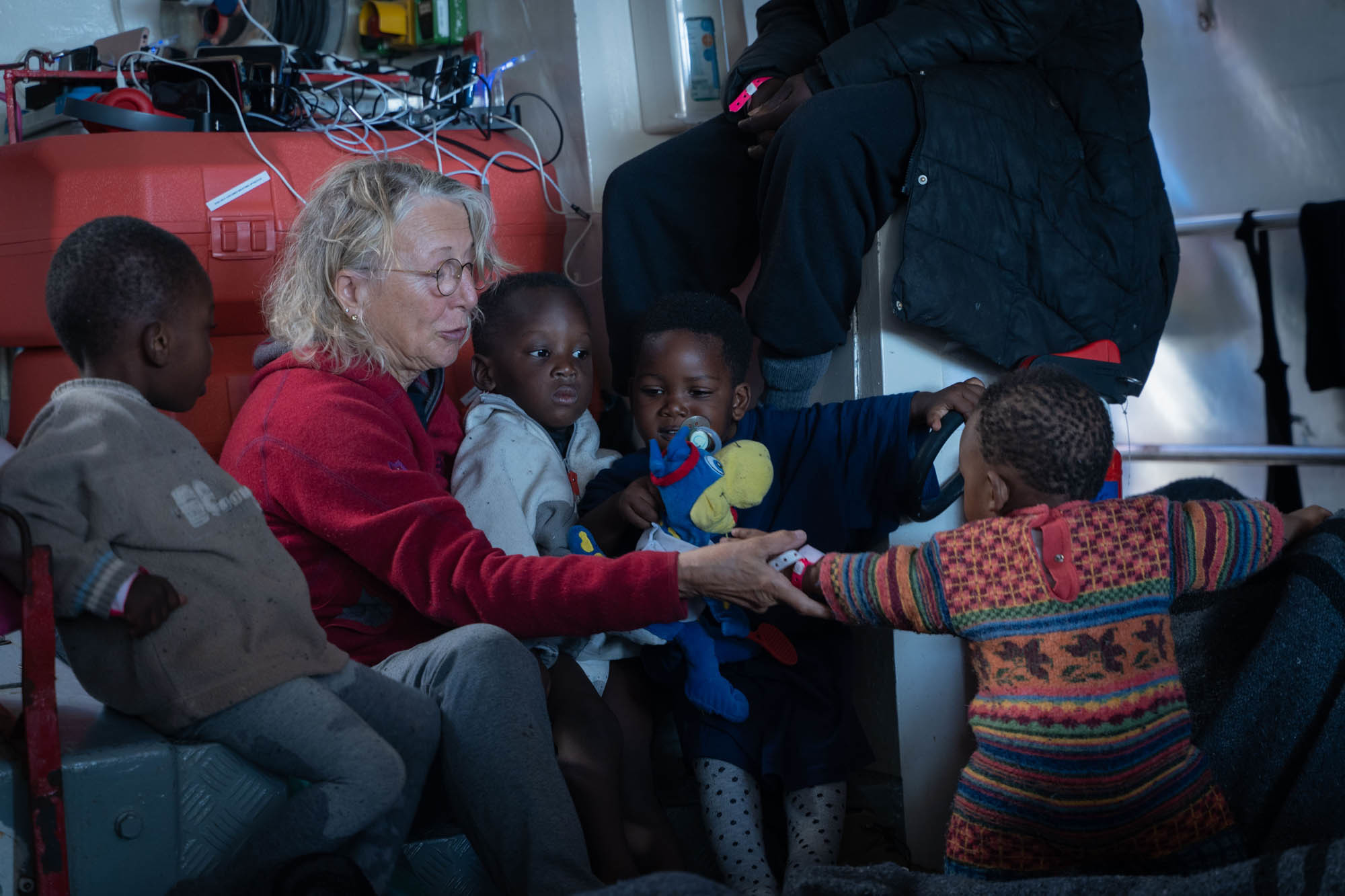 Una voluntaria cuida de varios niños en el barco de la ONG Mission Lifeline.