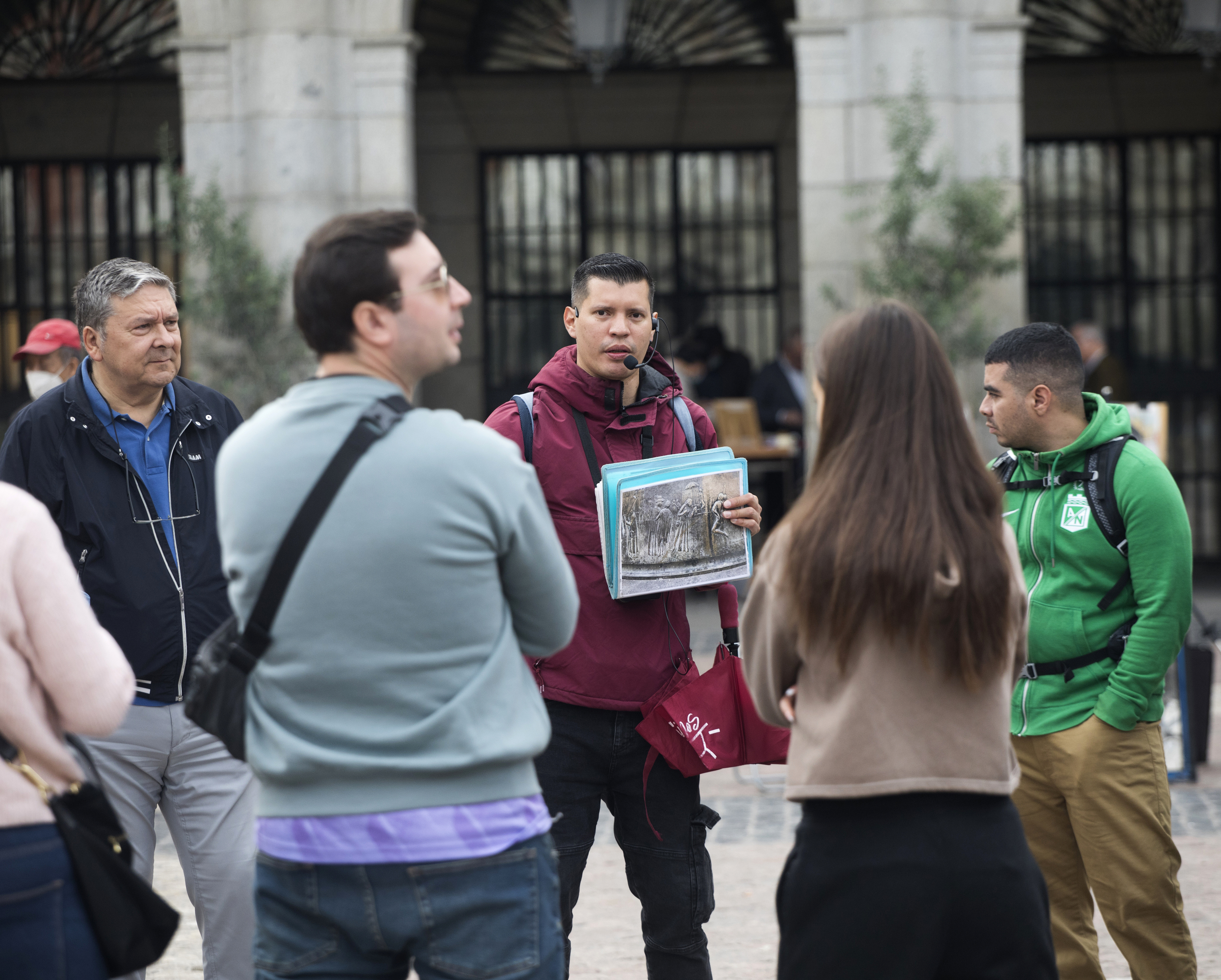 Un guía turístico explica a unos clientes la Plaza Mayor de Madrid.