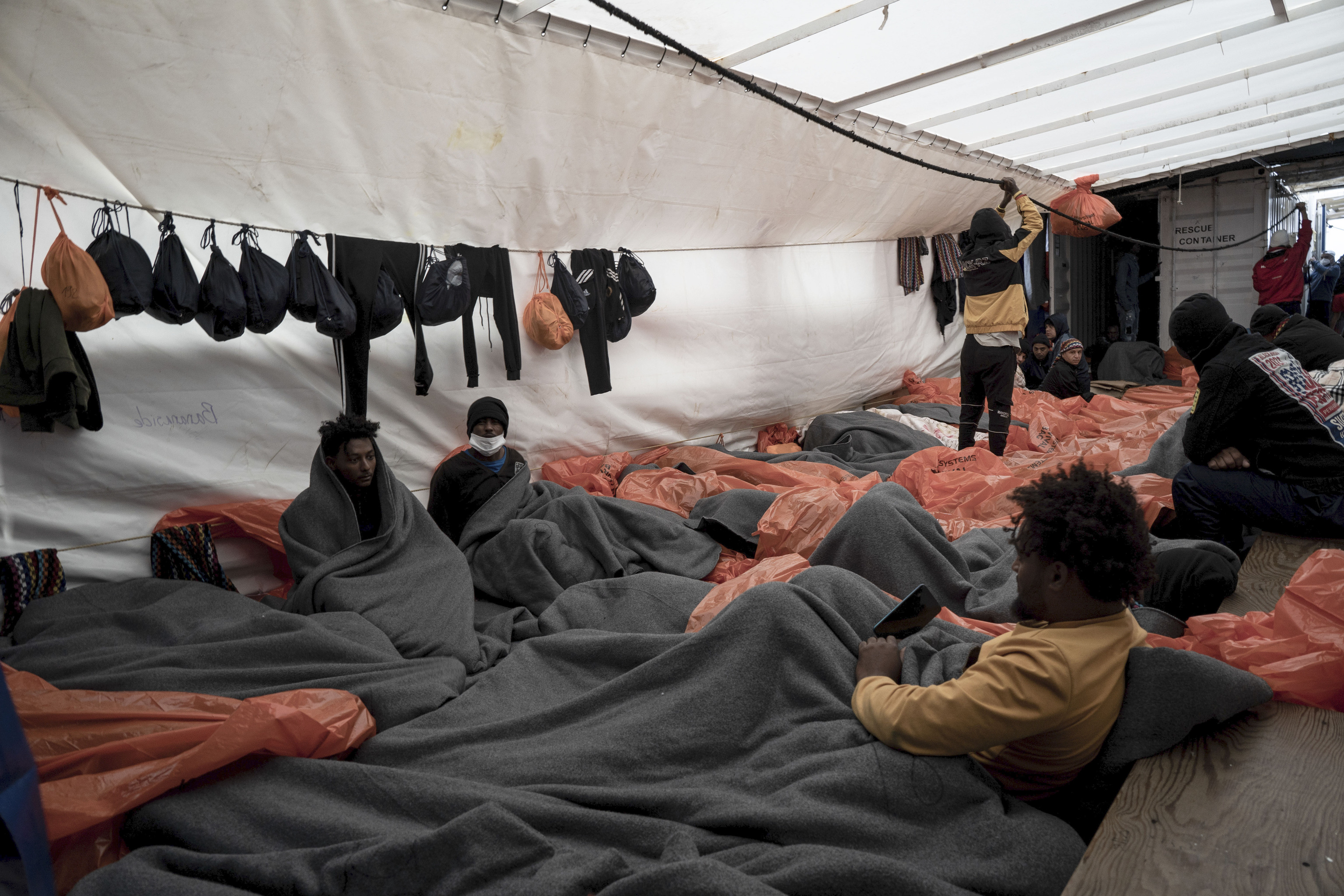 Los migrantes a bordo del Ocean Viking se envuelven en mantas y bolsas impermeables.