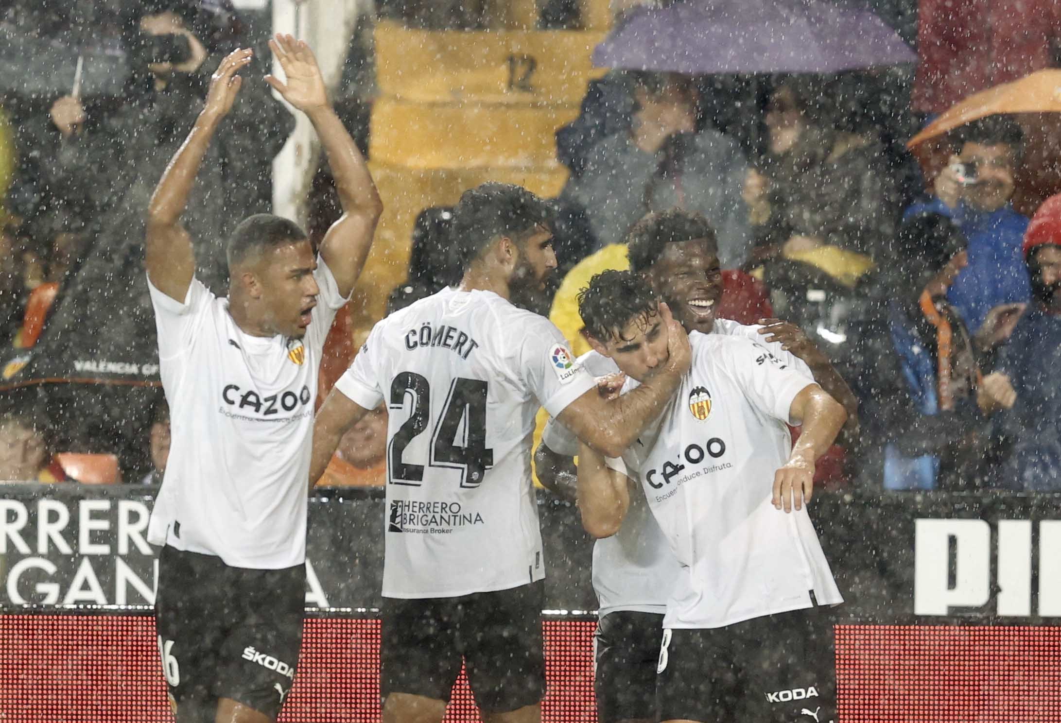 Los jugadores del Valencia abrazan a Almeida tras su gol de falta ante el Betis bajo la tormenta.