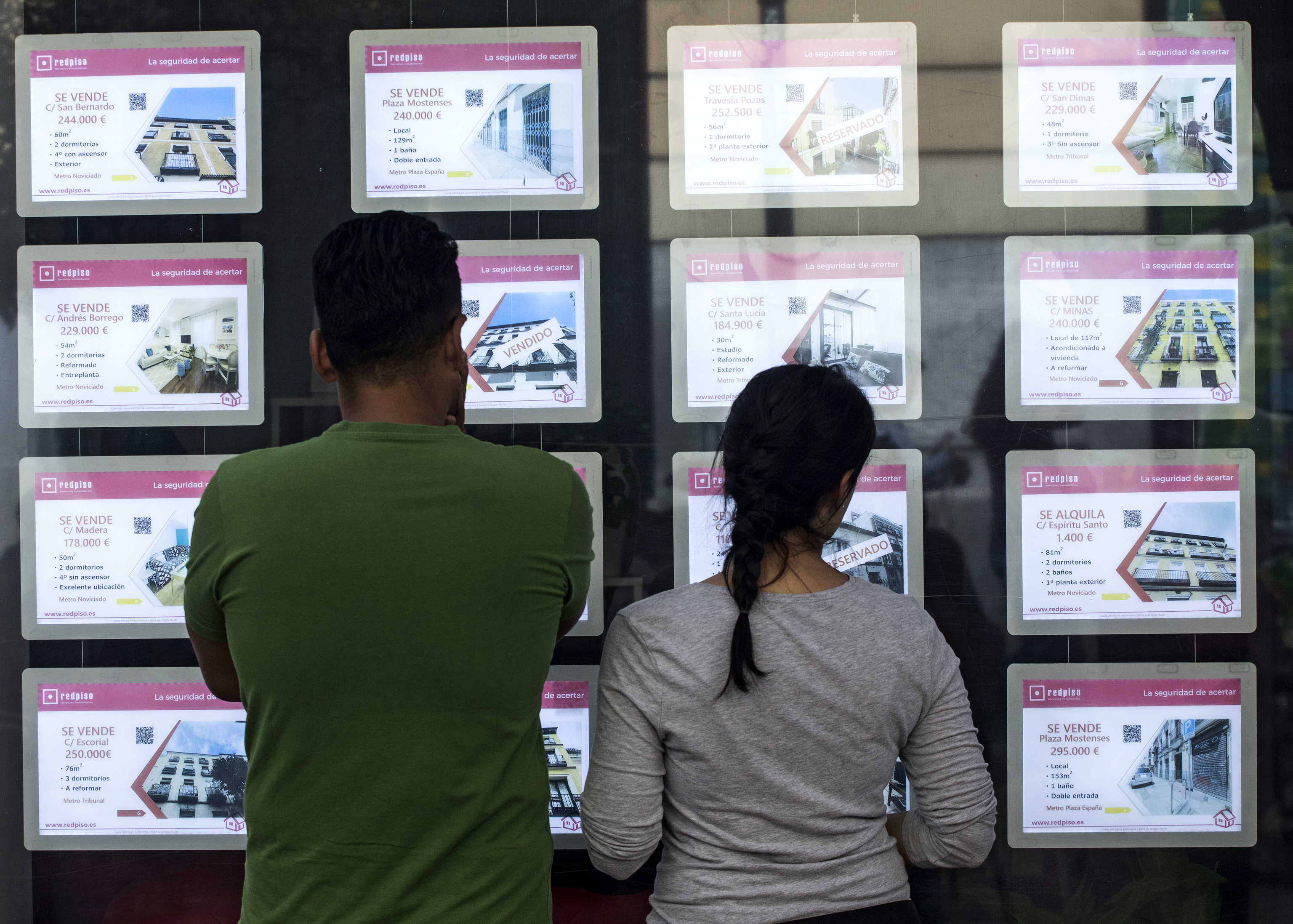 Dos personas observan anuncios en una inmobiliaria en Madrid.