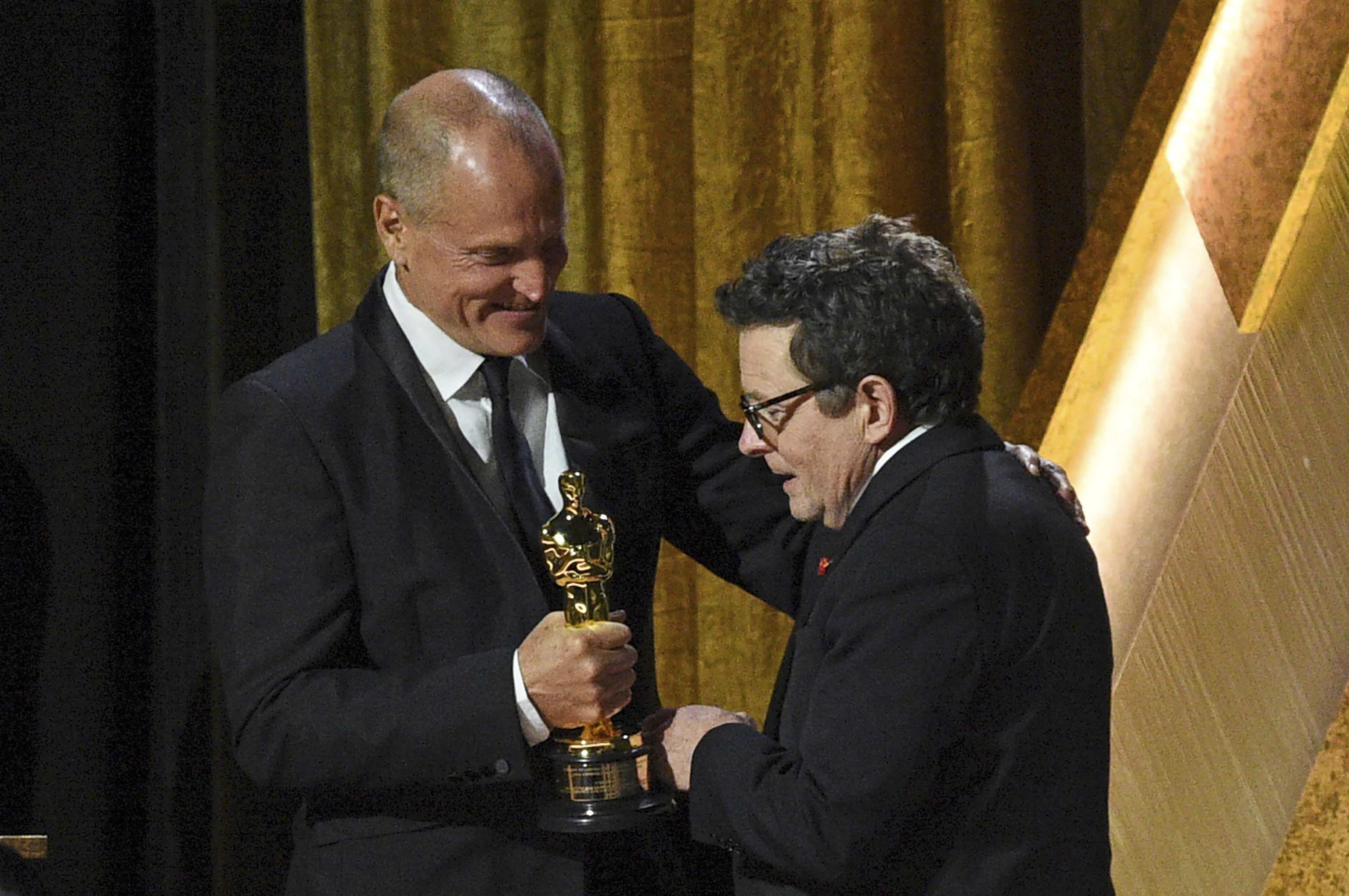 Michael J. Fox recoge su premio de manos de Woody Harrelson.