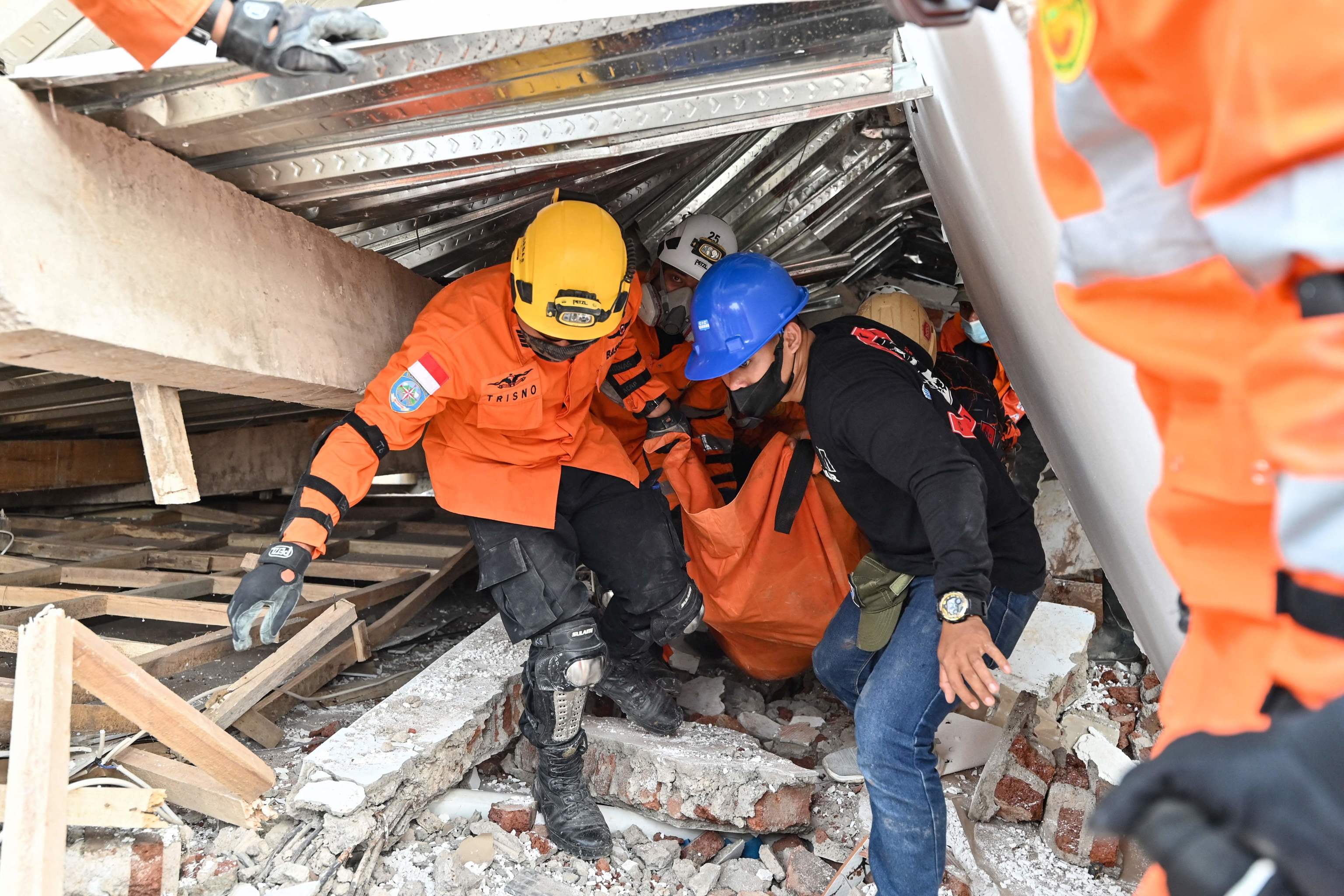 Two emergency workers remove the body of an earthquake victim in Cianjur.