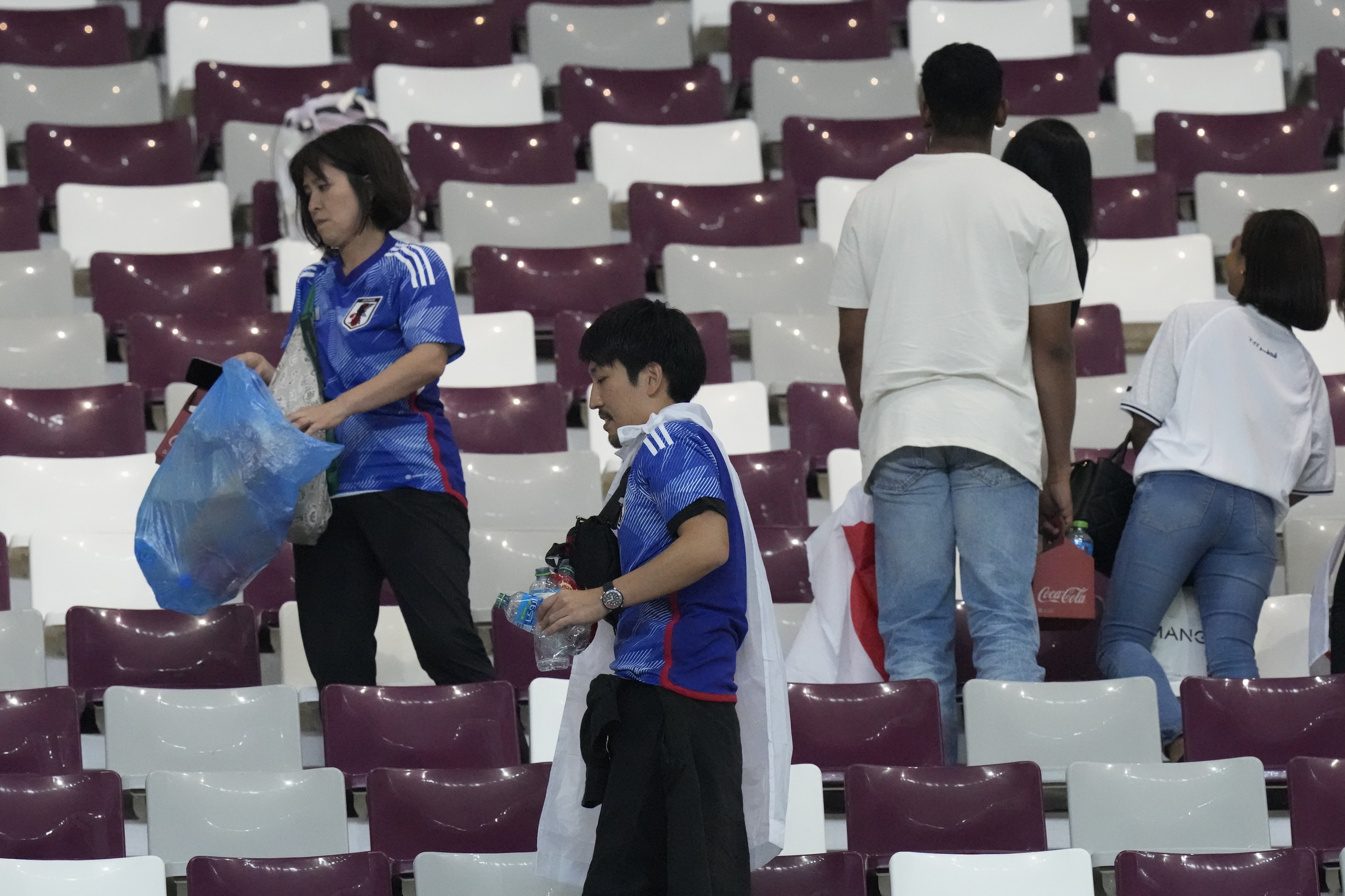 Aficionados nipones limpiando el Khalifa International Stadium tras su victoria ante Alemania,