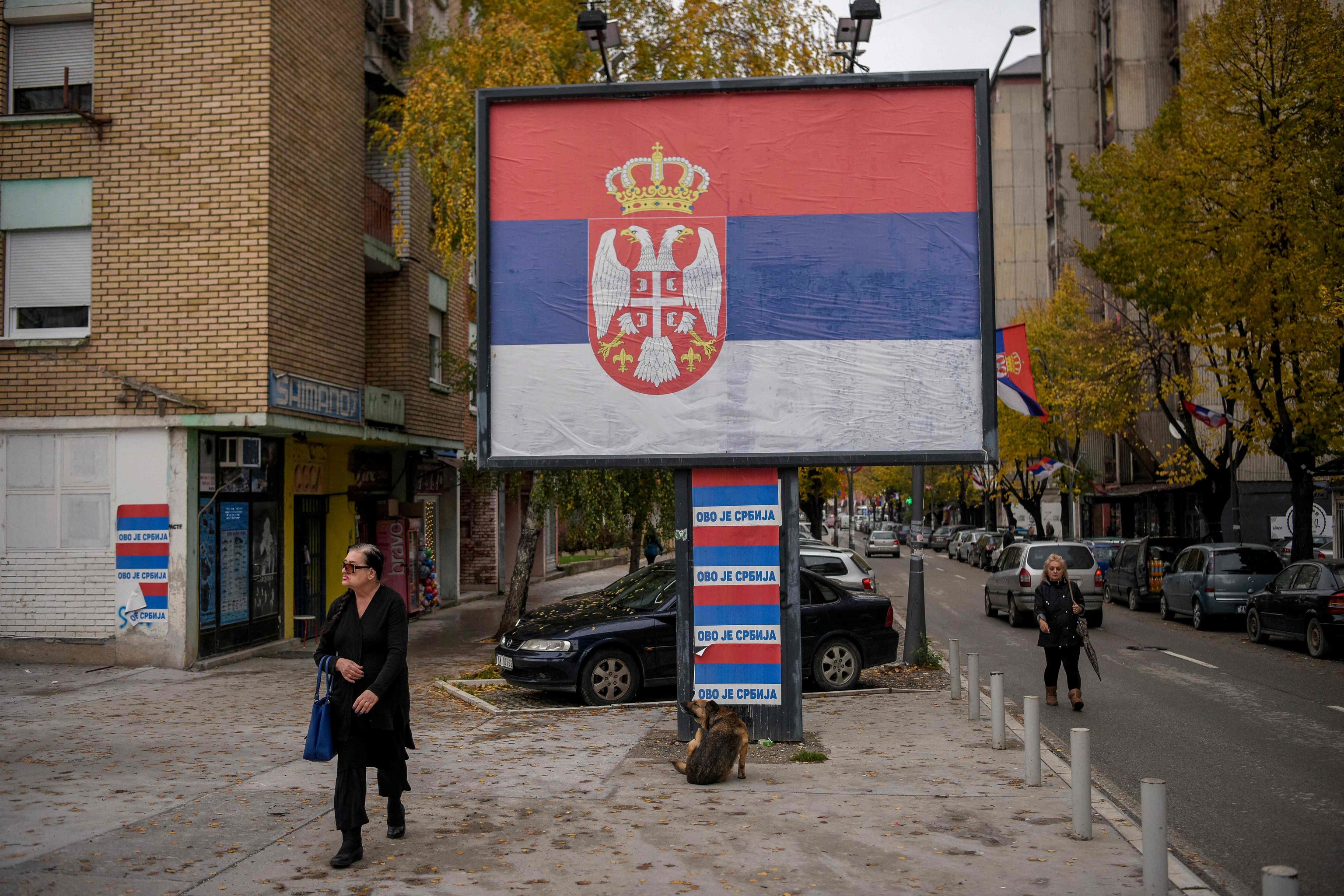 Una mujer pasa por delante de una valla publicitaria con la bandera serbia, en Mitrovica.