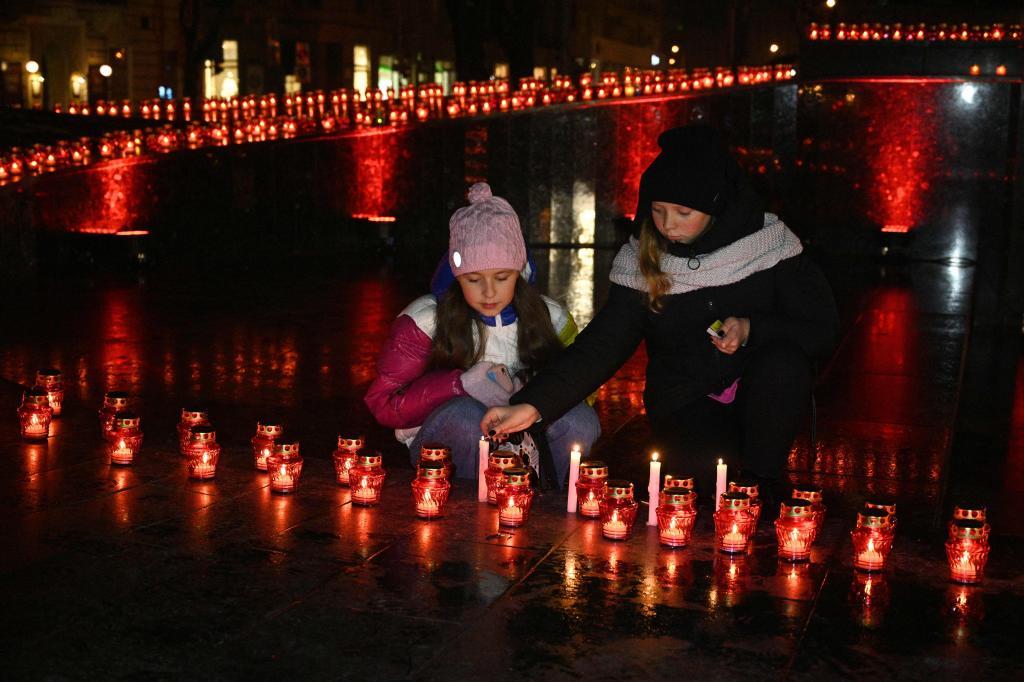 Two children attend a candlelit ceremony at a memorial to Holodomor victims in kyiv
