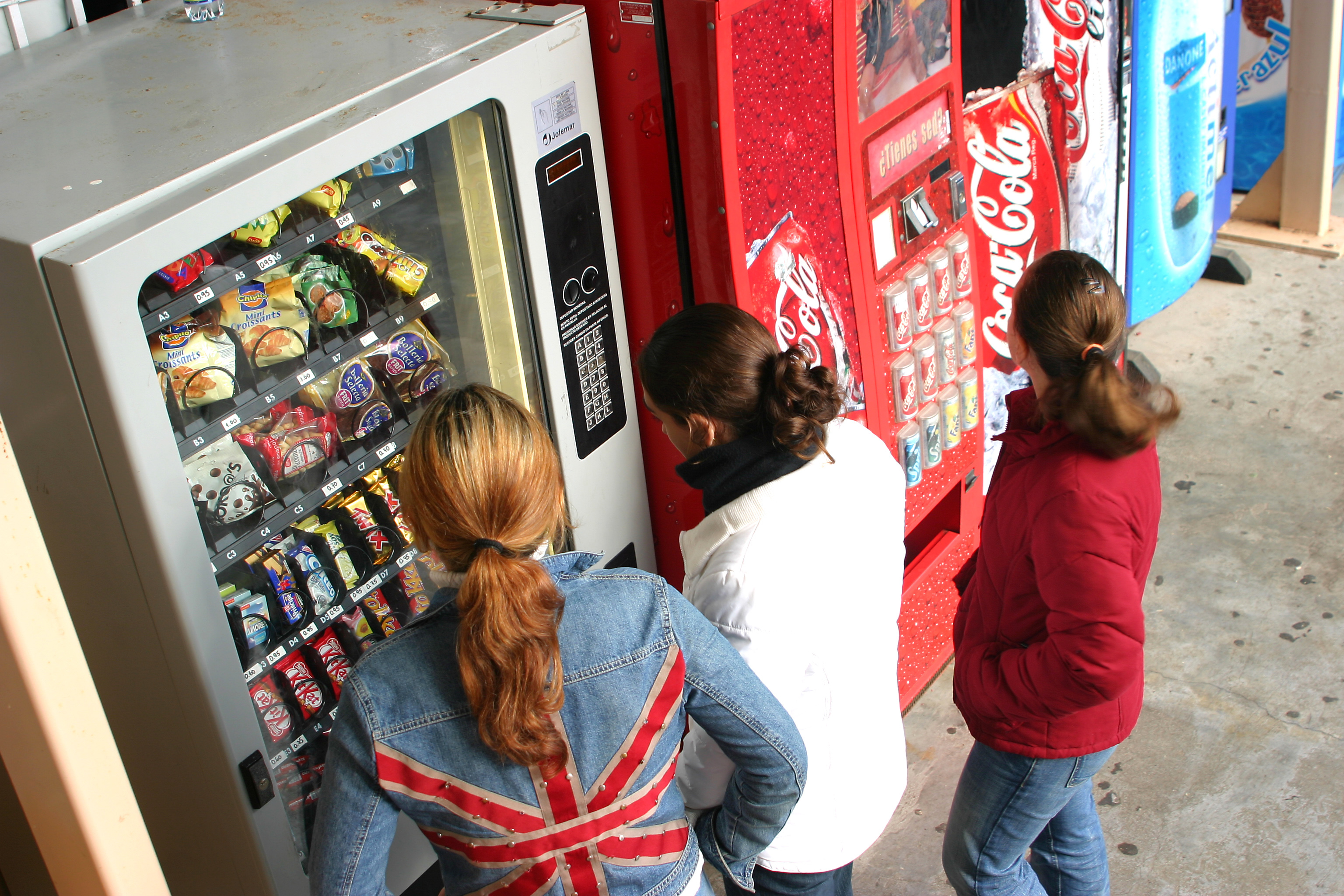 Unas niñas compran snacks y refrescos en máquinas de venta automática