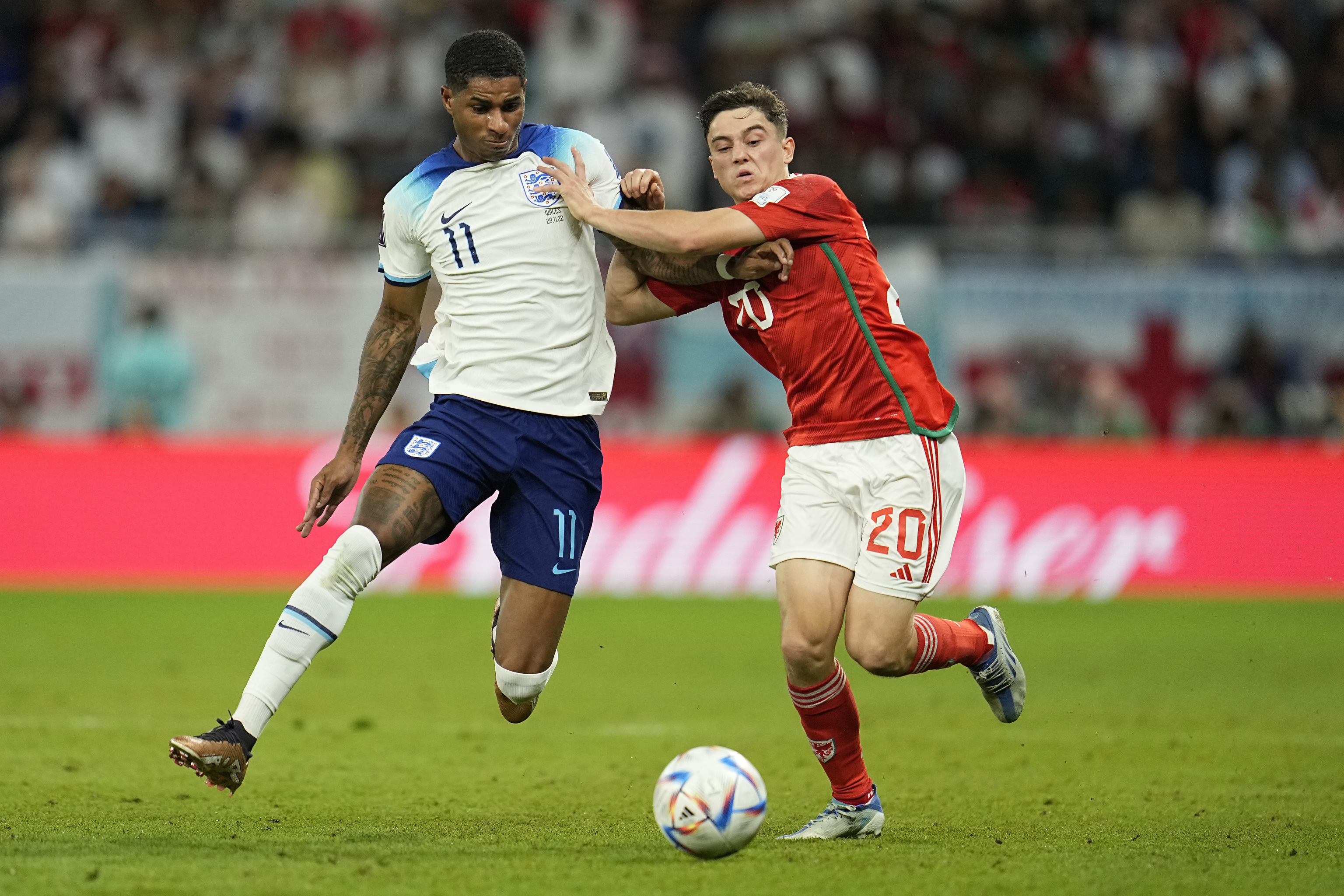 El jugador de Inglaterra Marcus Rashford y el galés Daniel James peleando un balón en el Mundial de Qatar 2022.