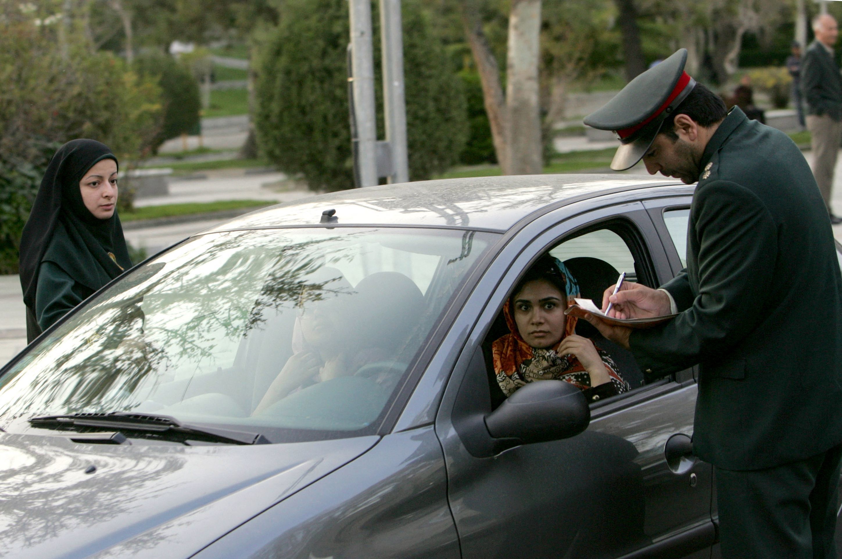 Un policía de la moral comprueba la vestimenta de dos mujeres en Teherán.