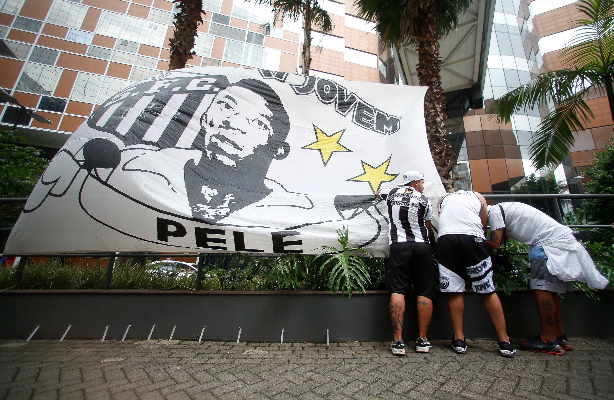 Un grupo de aficionados del Santos coloca una pancarta en la puerta del hospital donde est ingresado Pel.