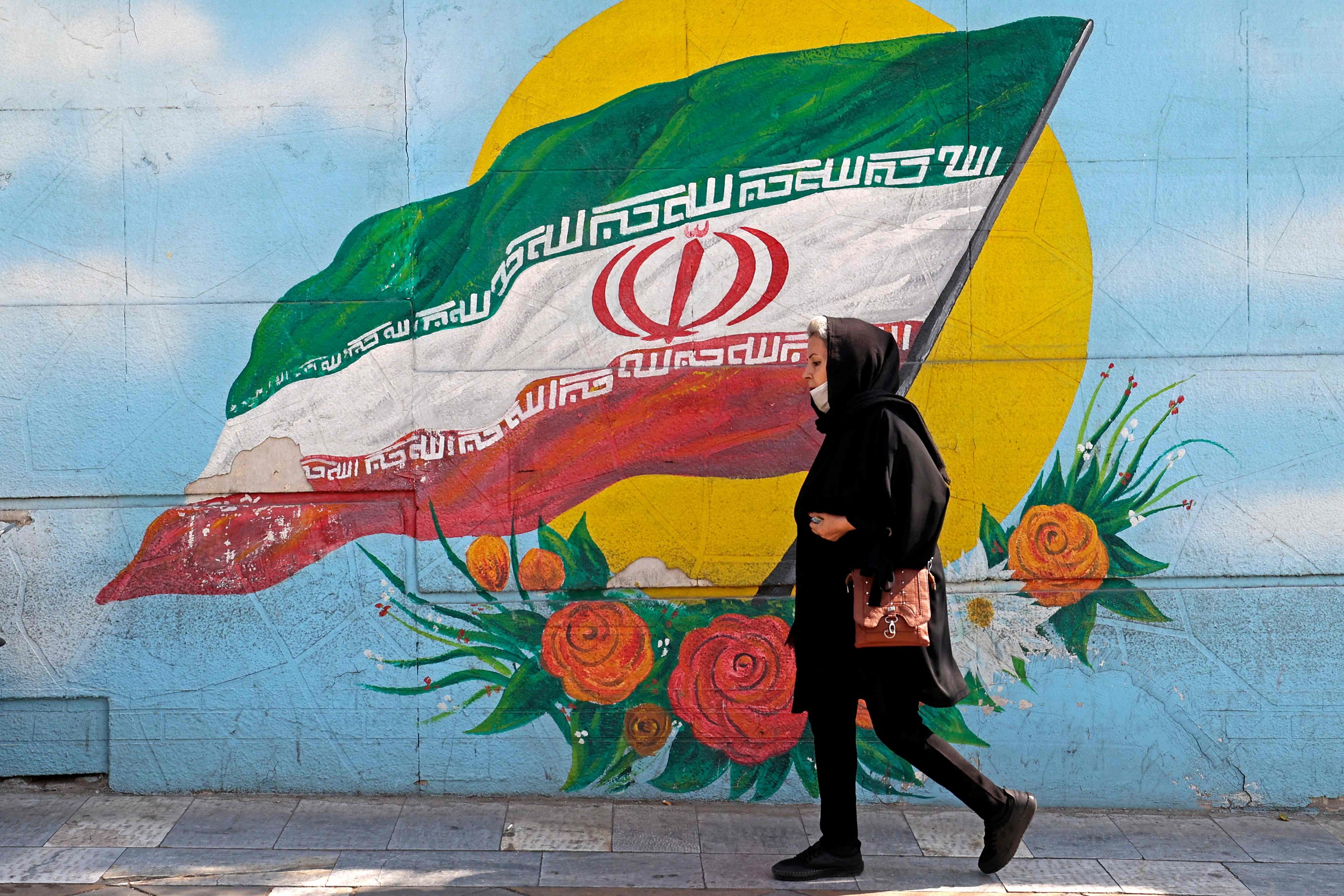 Una mujer camina junto a un mural en Teher