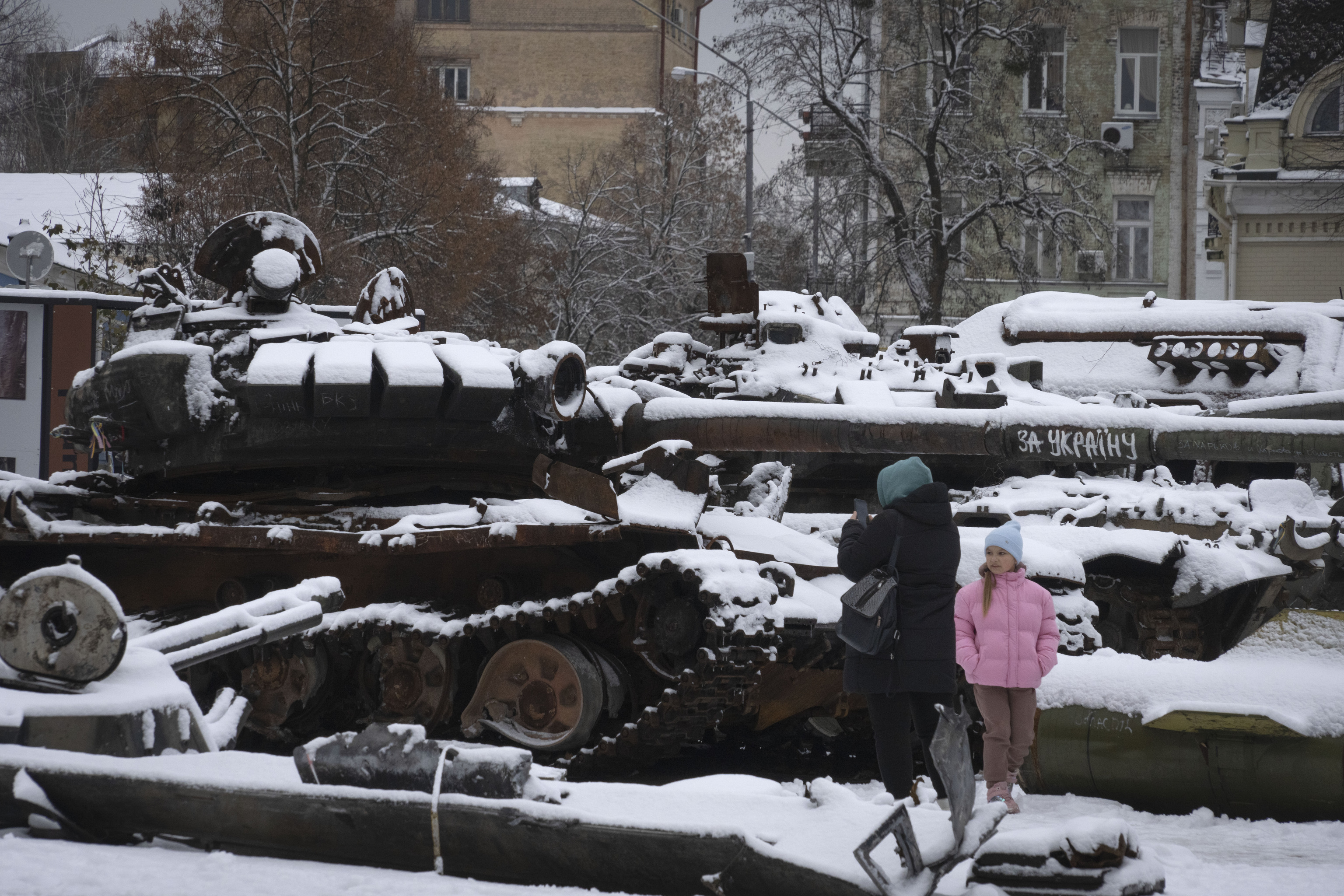 Civiles en Kiev pasan junto a un tanque ruso destruido cubierto de nieve.